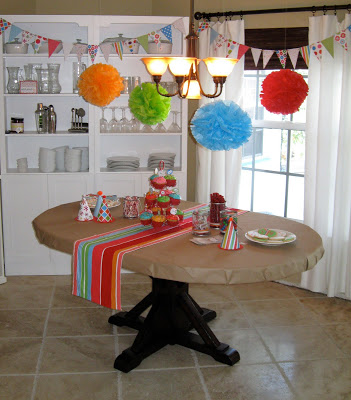 Homemade banners and pompoms look colorful and cheery above the birthday table. 