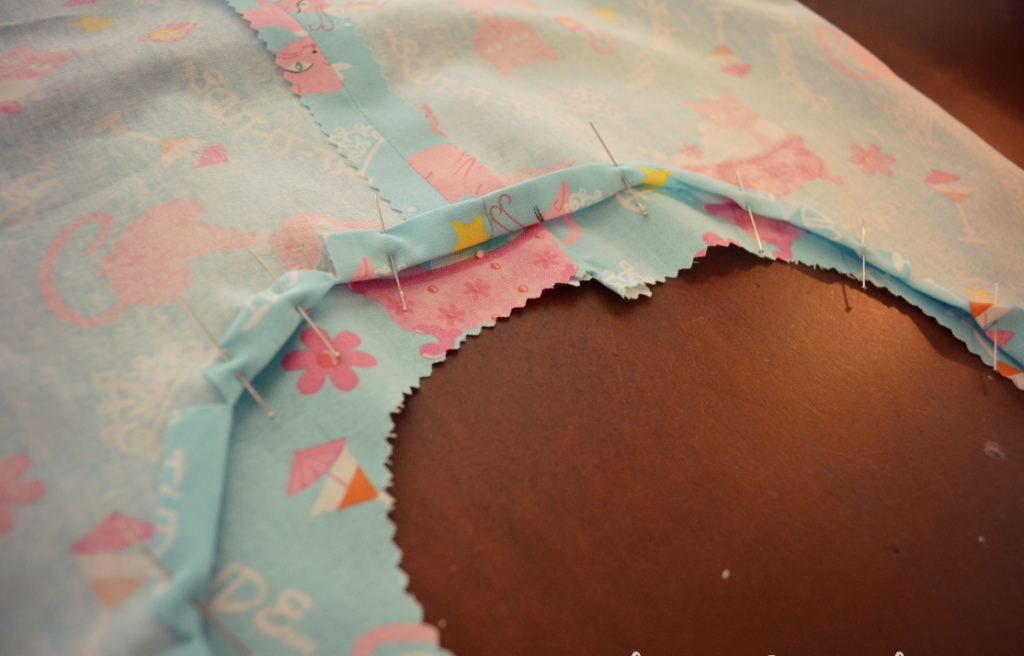 Fold in and pin down the neck of the dress to prepare for hemming. 