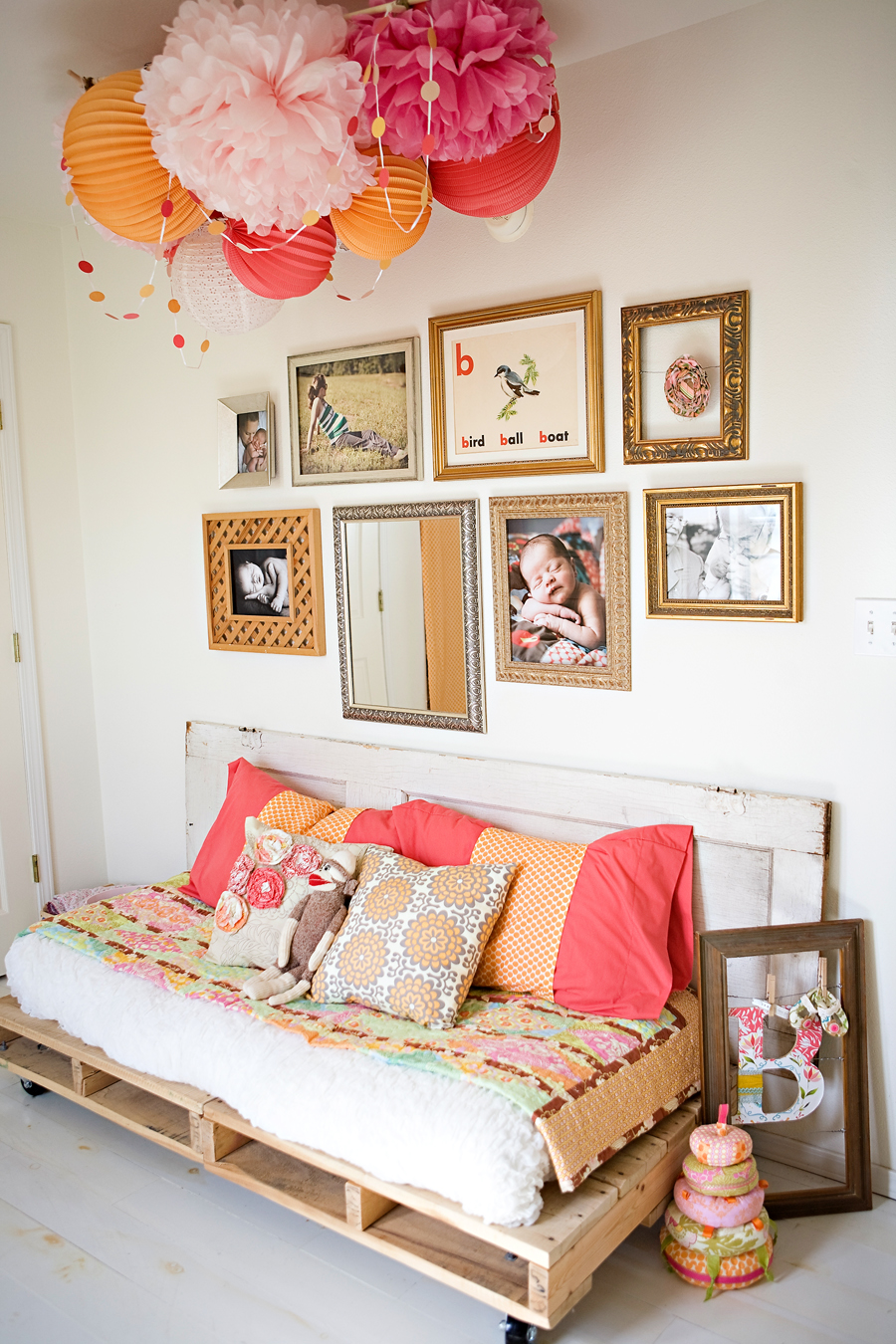 Simple items like inexpensive paper lanterns, garland and even reclaimed pallets and a door look fun, bohemian and eclectic under a gallery wall of fun frames. 