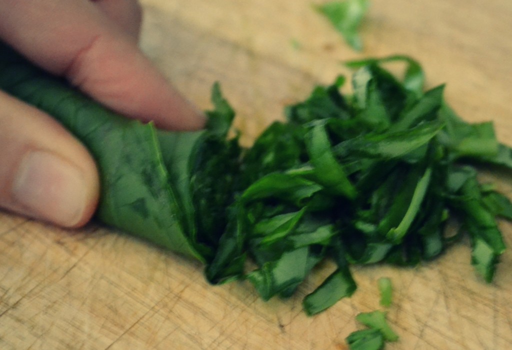 Chop the basil leaves by rolling them tightly together and cutting them in slices. 