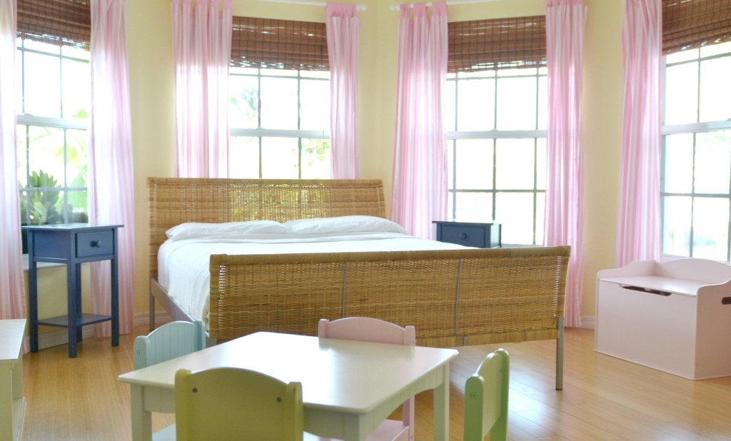 My daughters' bedroom after we cleaned out all their toys: just a bed, furniture and pink curtains.