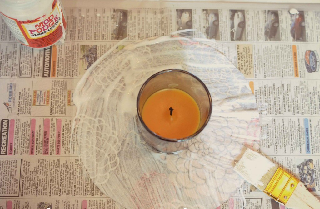 Center the candle and brush the fabric with Modg Podge is the next part of the easy DIY Fabric-Covered Candle process.