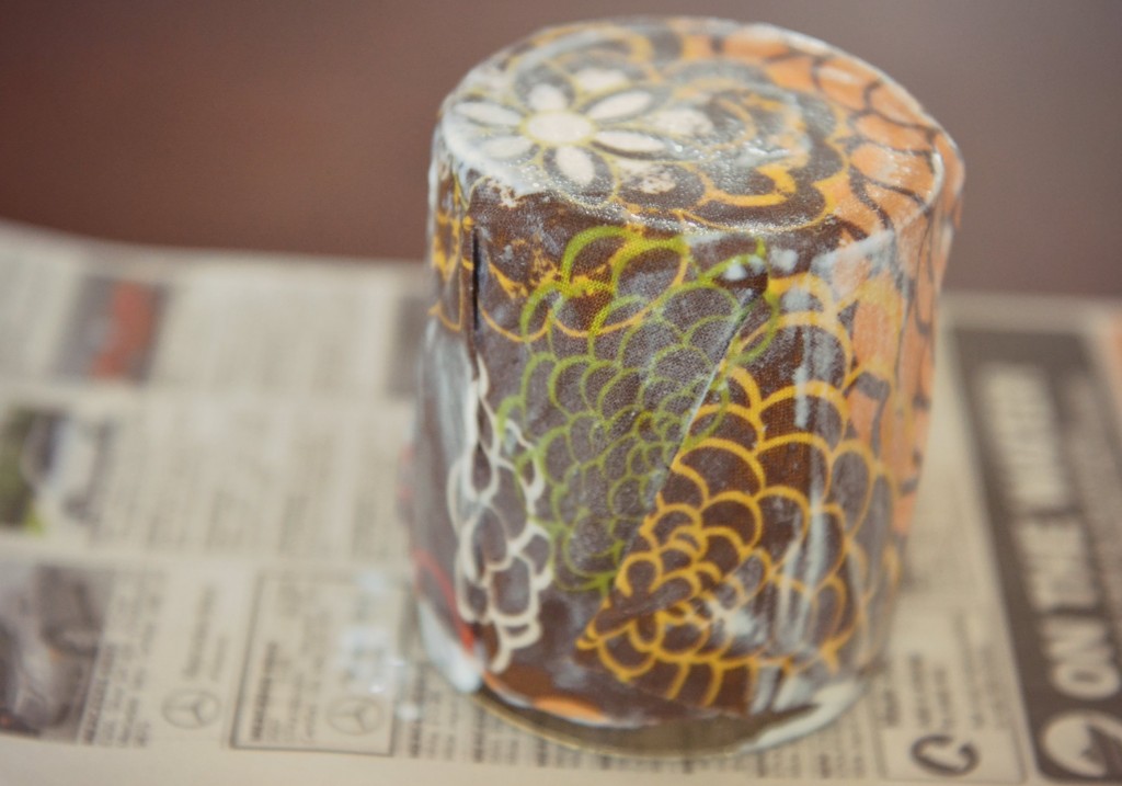 The next step in making an easy DIY Fabric-Covered Candle is to fold the fabric around the jar. 