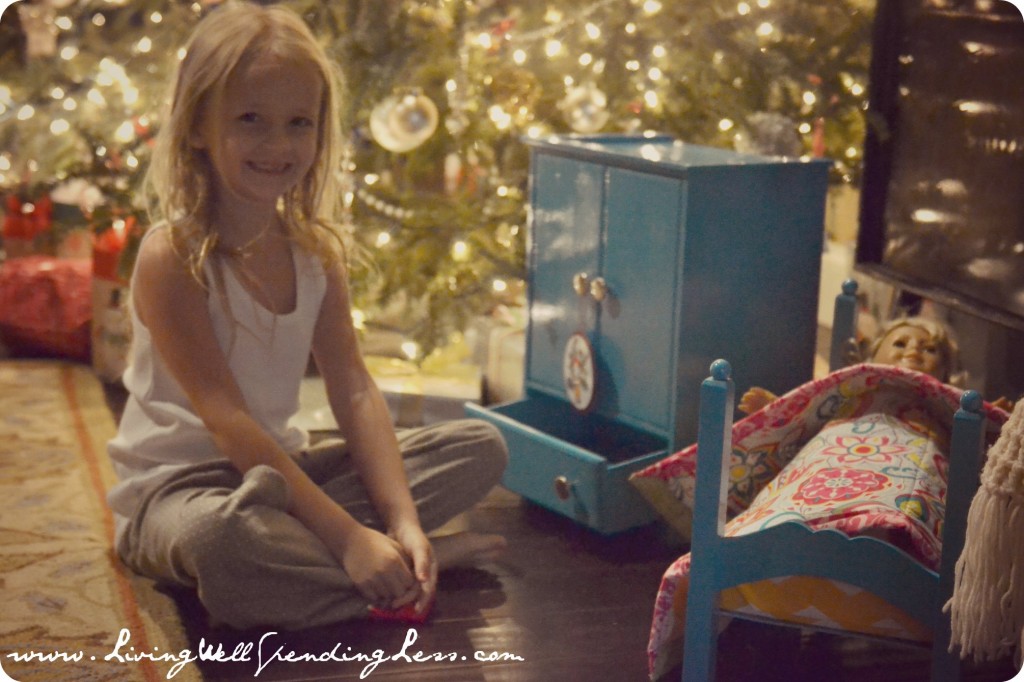 A content girl smiling next to her finished doll armoire next to the Christmas tree. 