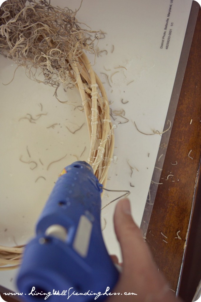  Spread hot glue over a section of the wreath then secure Spanish moss to wreath. 