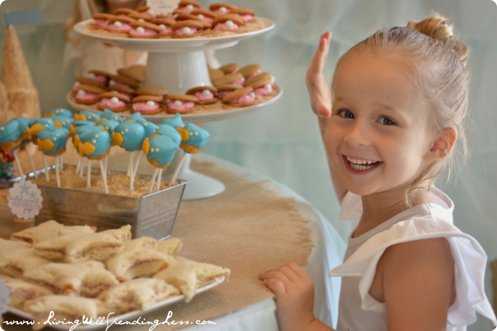 The birthday girl by the table of beach-themed party treats. 