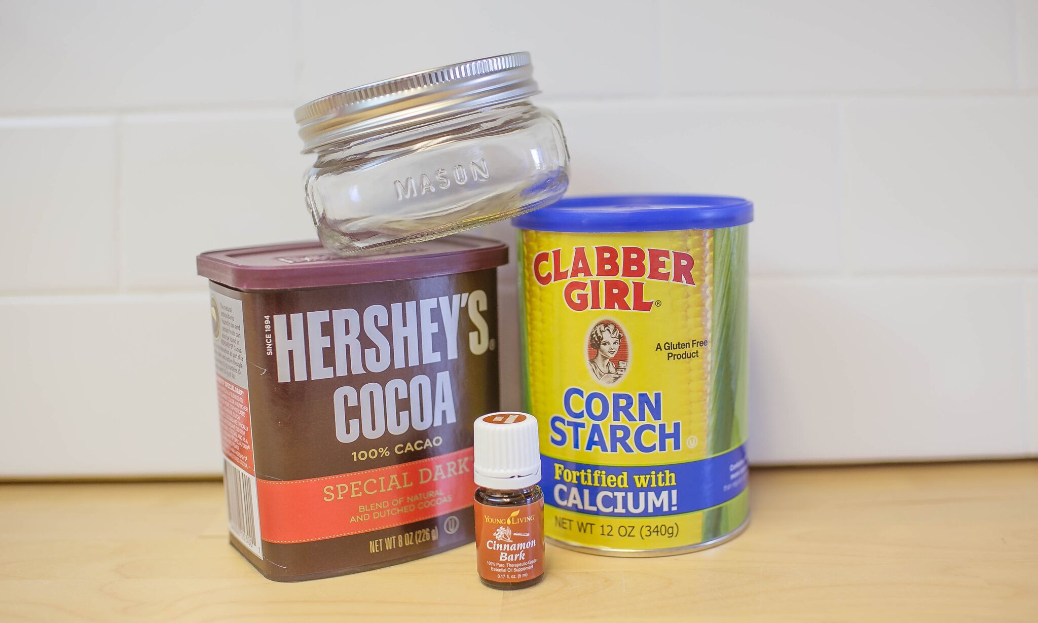 Assemble your materials to make DIY dry shampoo: Cocoa powder, essential oil, corn starch and a mason jar. 