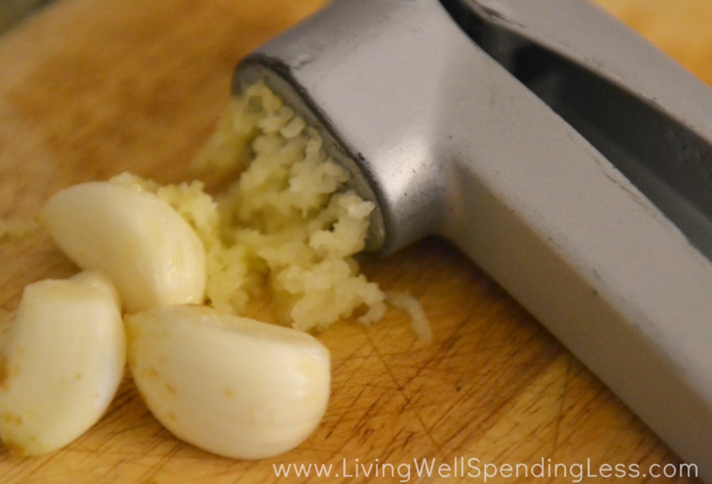 Mince garlic in a garlic press