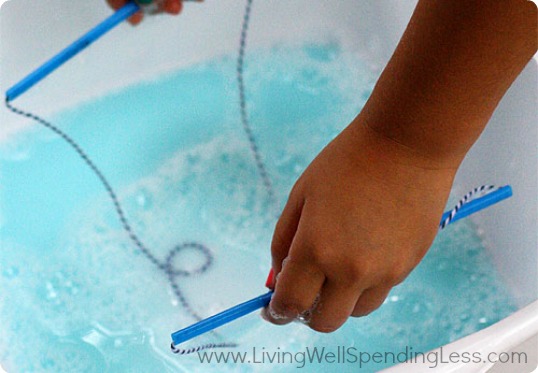 Add mixture of water, Dawn liquid detergent, corn starch, baking powder and corn syrup into a large container the straws can fit into. 