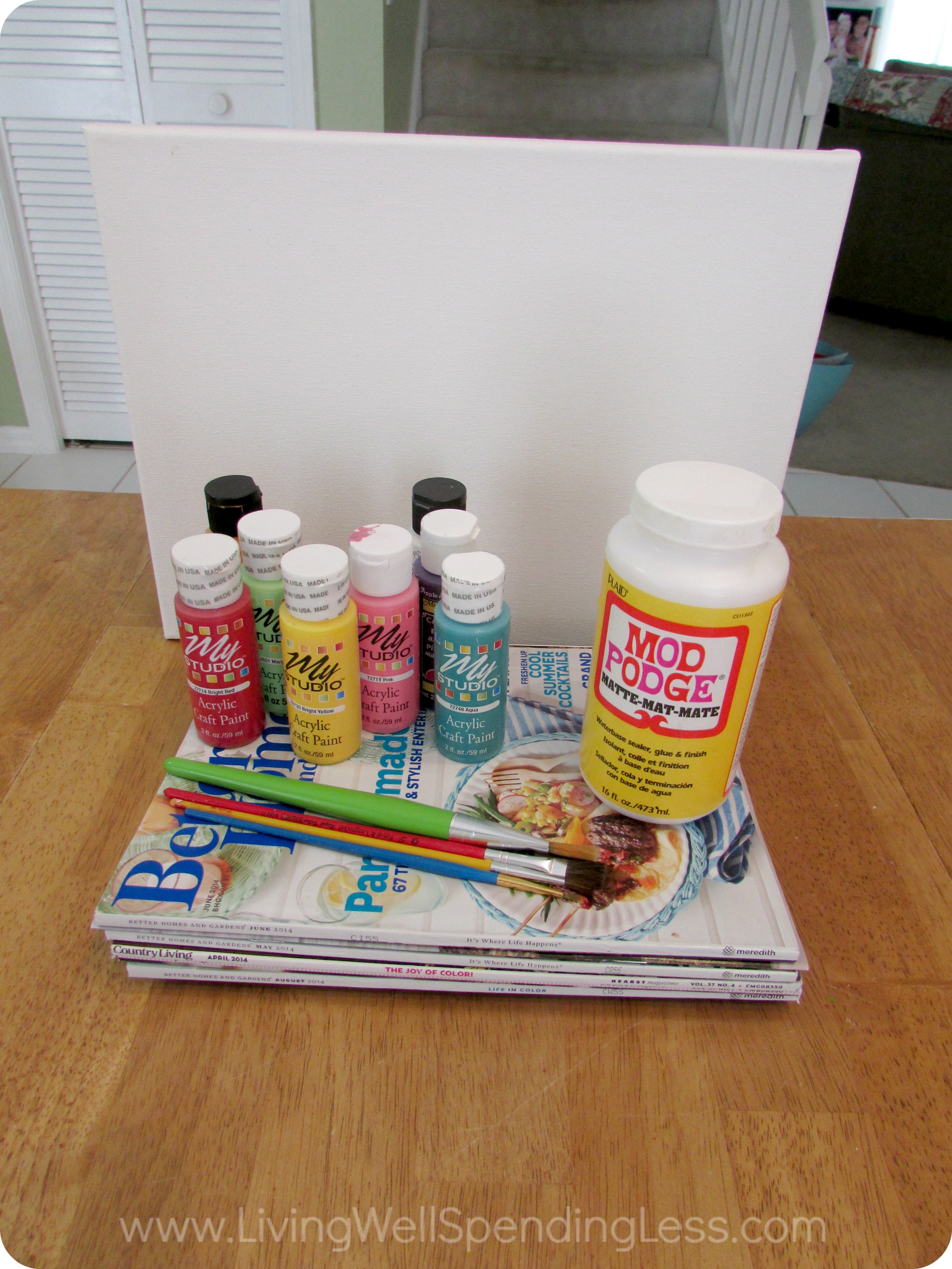 Gather all the necessary materials: Canvases, acrylic paints, paint brushes, old magazines, scissors and Mod Podge. 