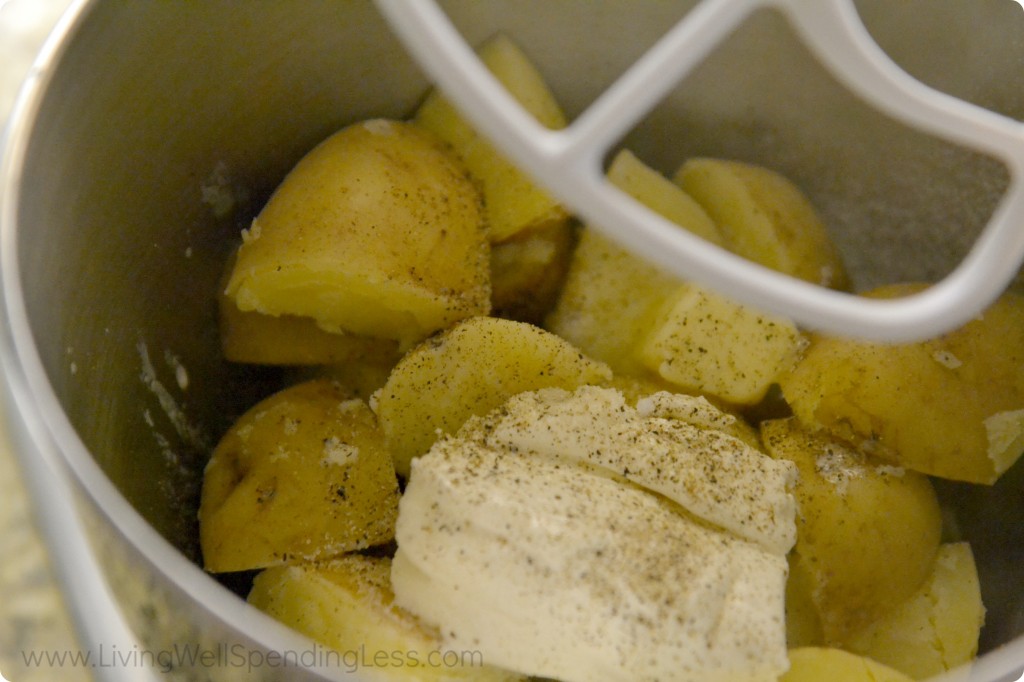 Add cooked potatoes to electric mixer and combine with sour cream, cream cheese, heavy cream, salt and pepper. 