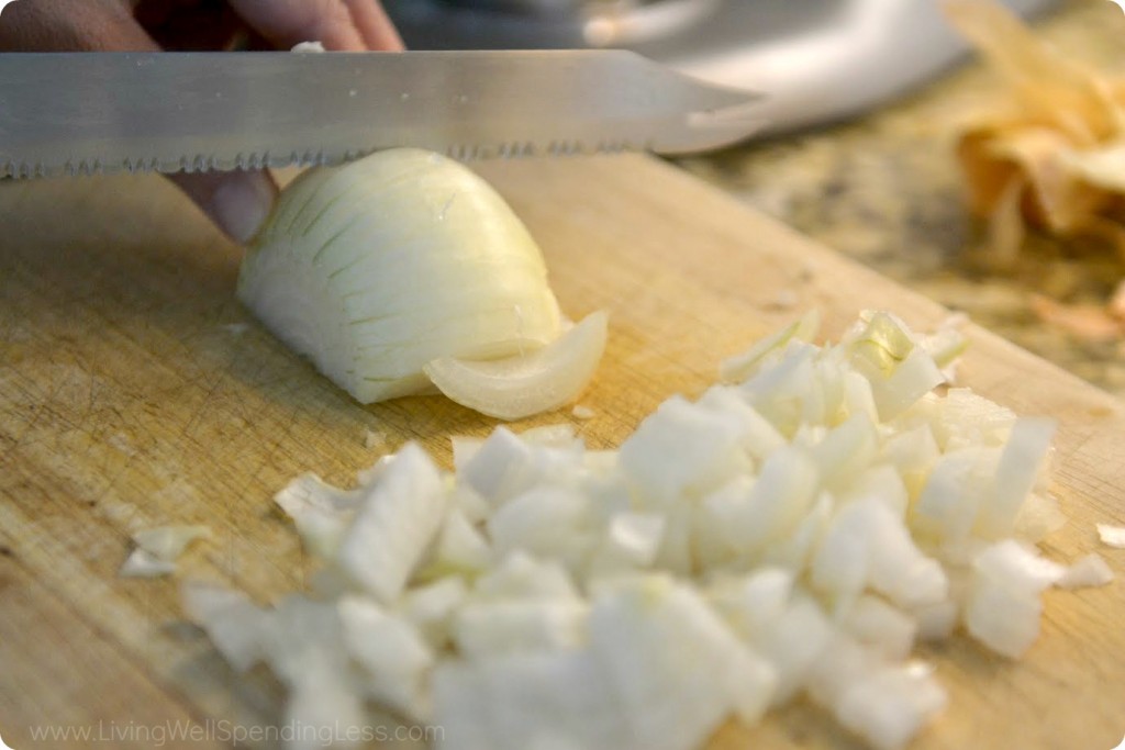 Chop onion on wooden cutting board. 