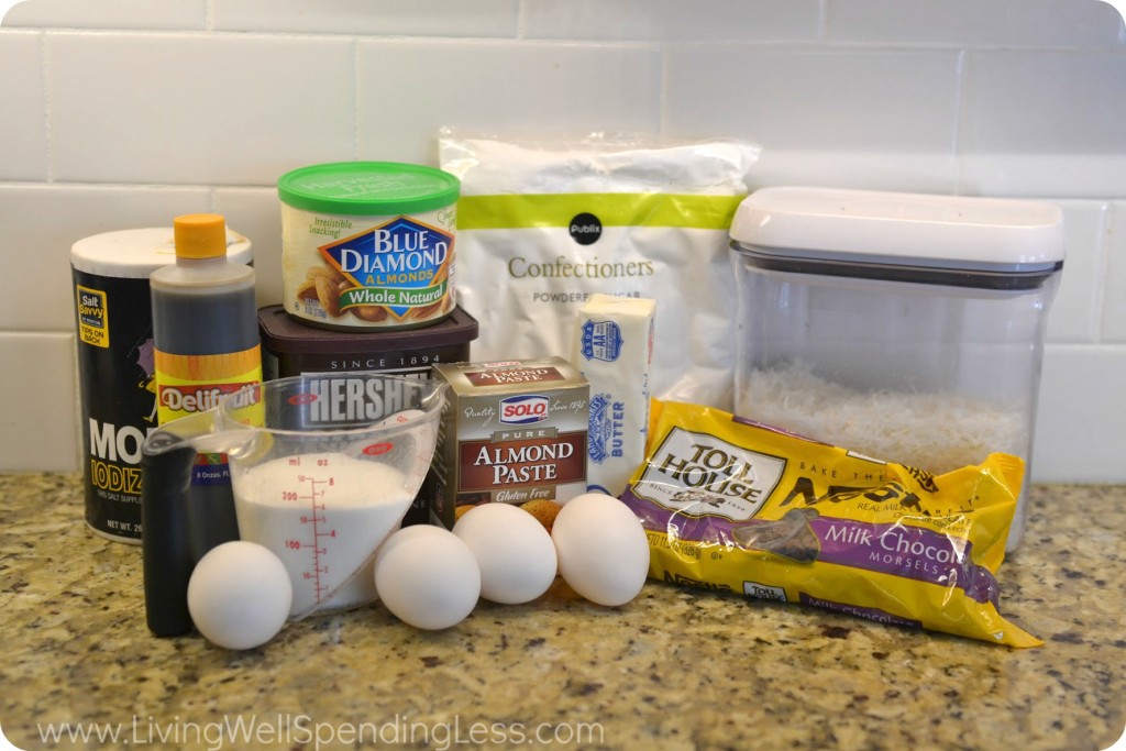 Assemble your ingredients for the flourless almond joy cake: chocolate chips, butter, almond paste, shredded coconut, powdered sugar, sugar, eggs, vanilla, salt, cocoa powder, and whole almonds. 