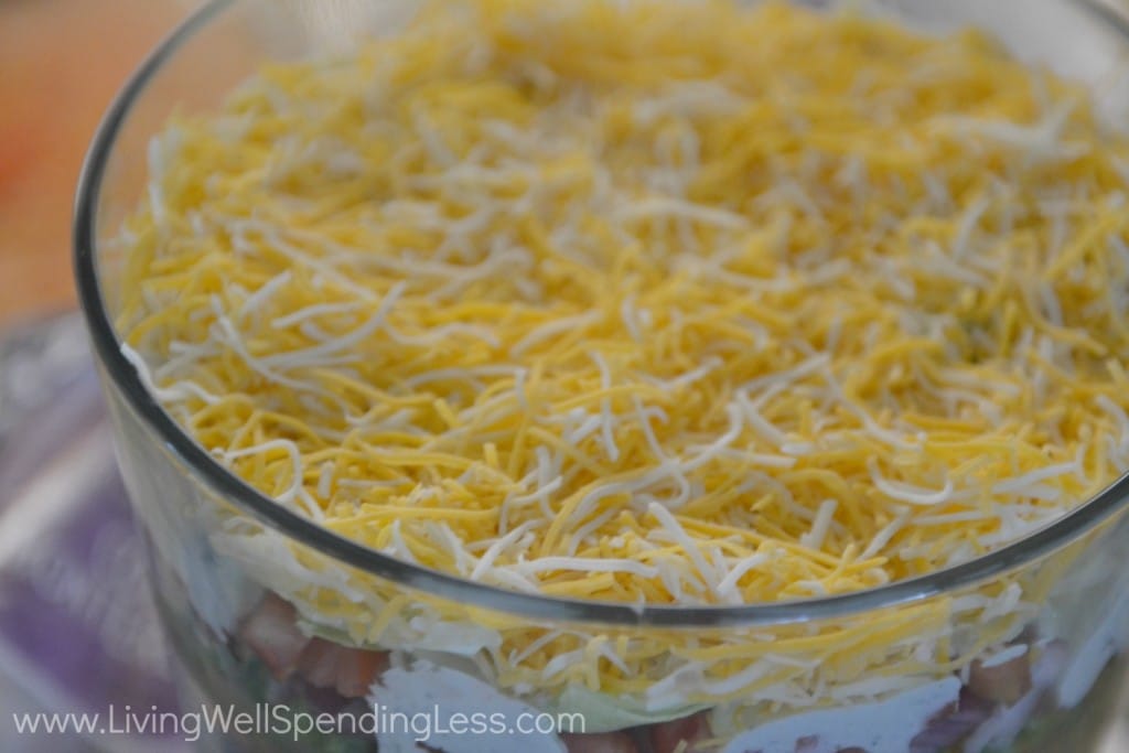 After adding the dressing layer to your salad, top with a layer of shredded cheese. 