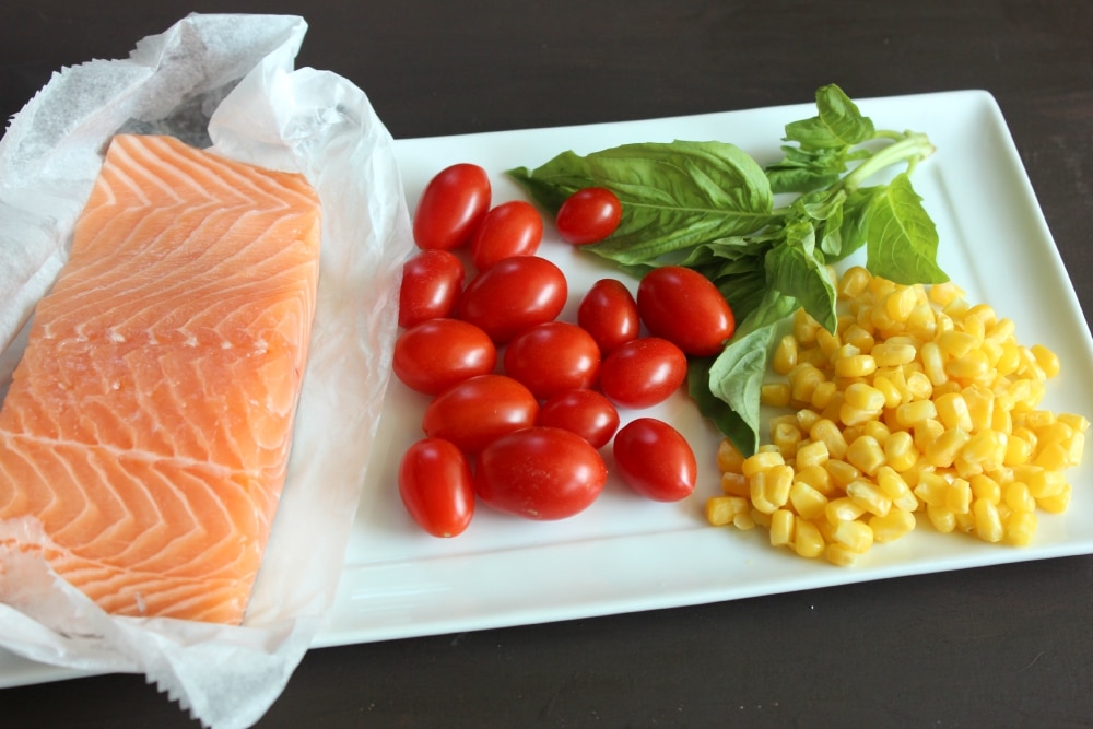 Assemble your ingredients: salmon, cherry tomatoes, basil, and corn. 