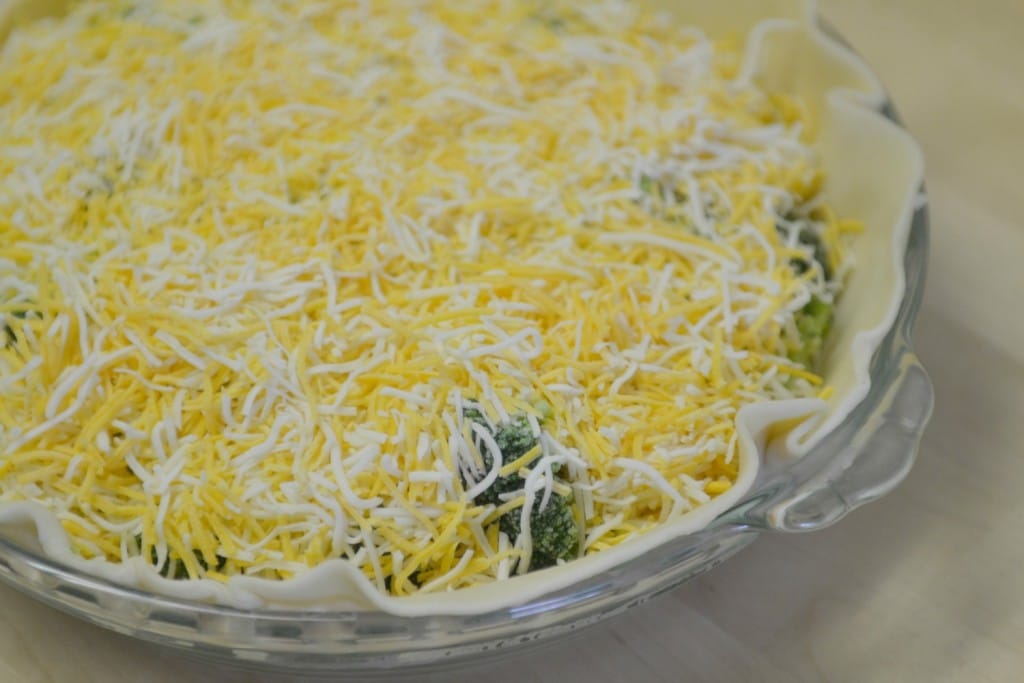 Top the vegetables with a layer of shredded cheese to form the filling of your quiche.