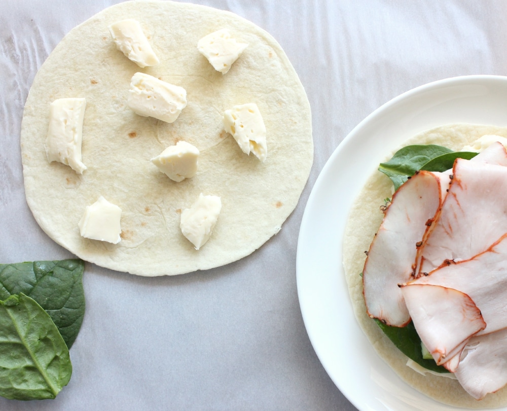 Layer brie cheese with spinach and turkey on the torilla