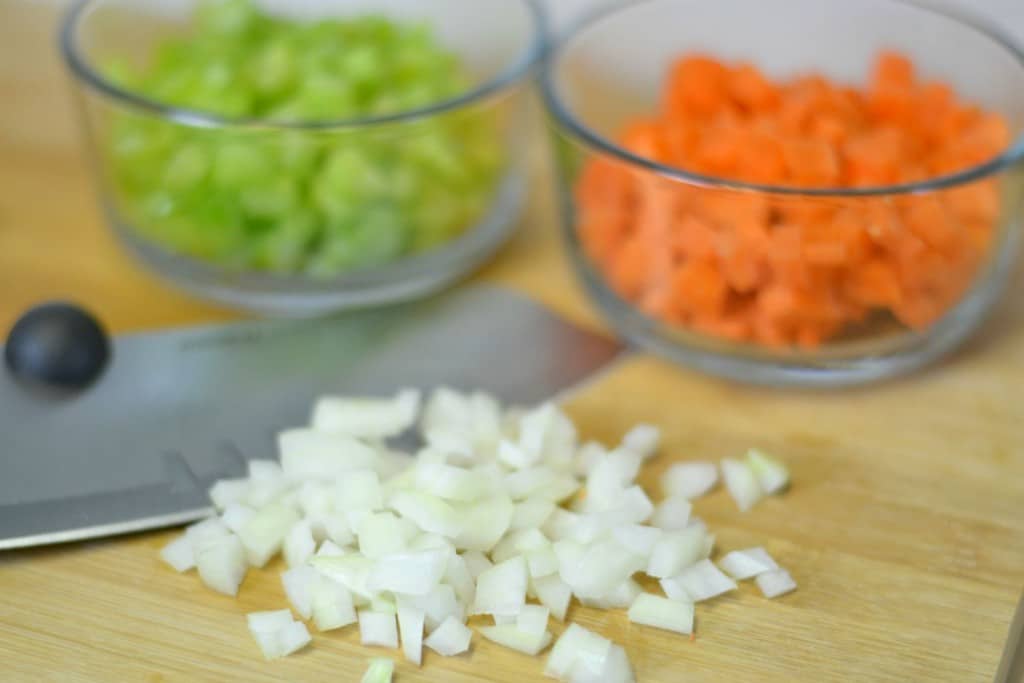 Chop onions, carrots, and celery for soup