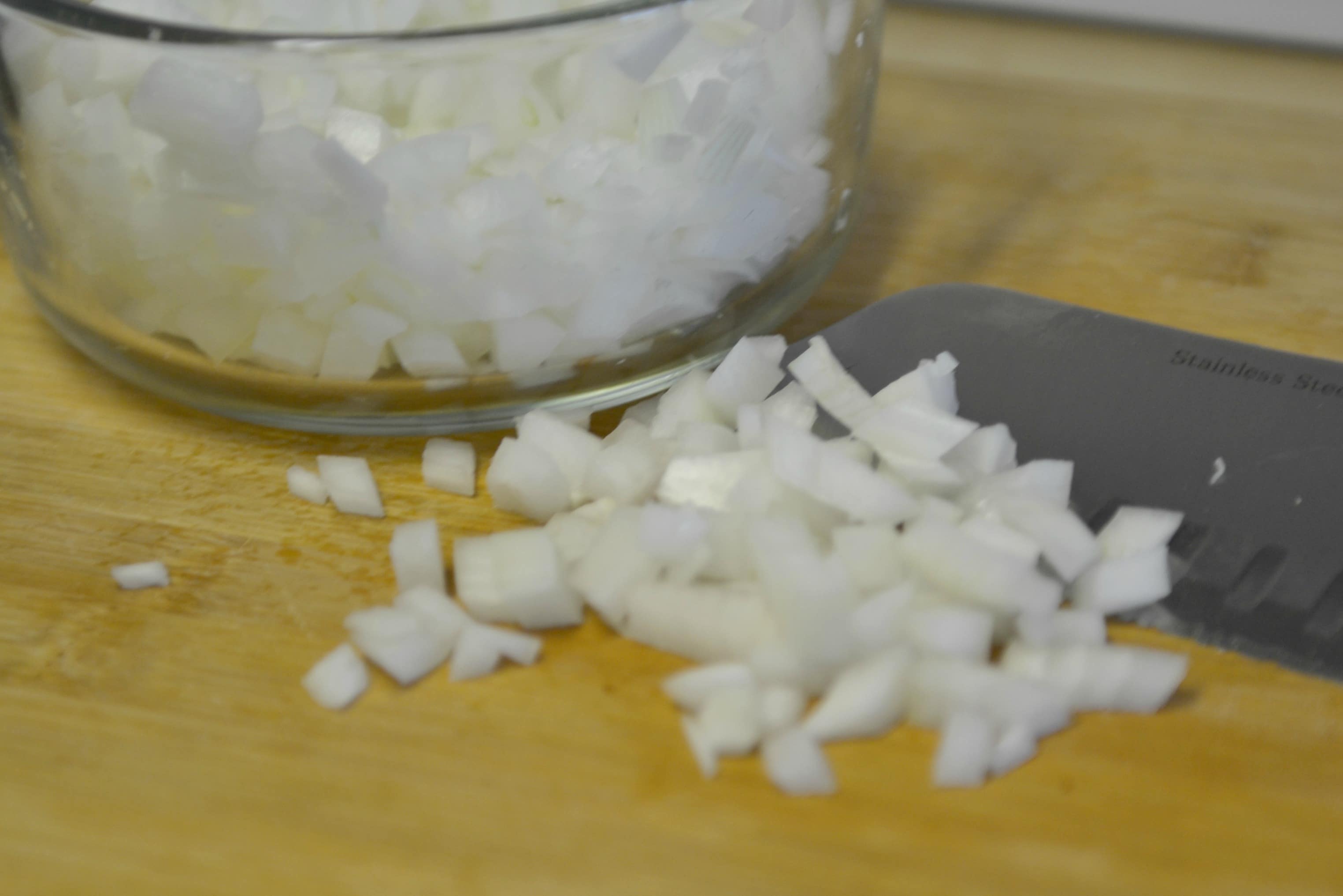 The next step of the slow cooker bacon and beans recipe is to chop an onion.