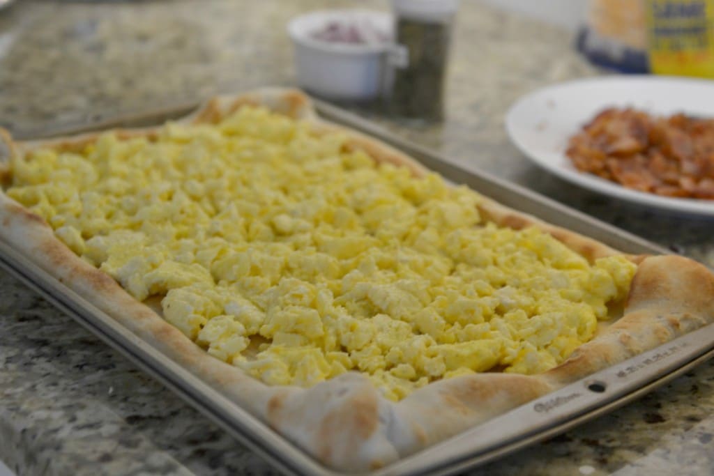 Spread scrambled eggs onto browned pizza crust. 