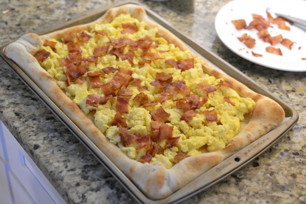 Add bacon over the scrambled eggs on pizza crust. 
