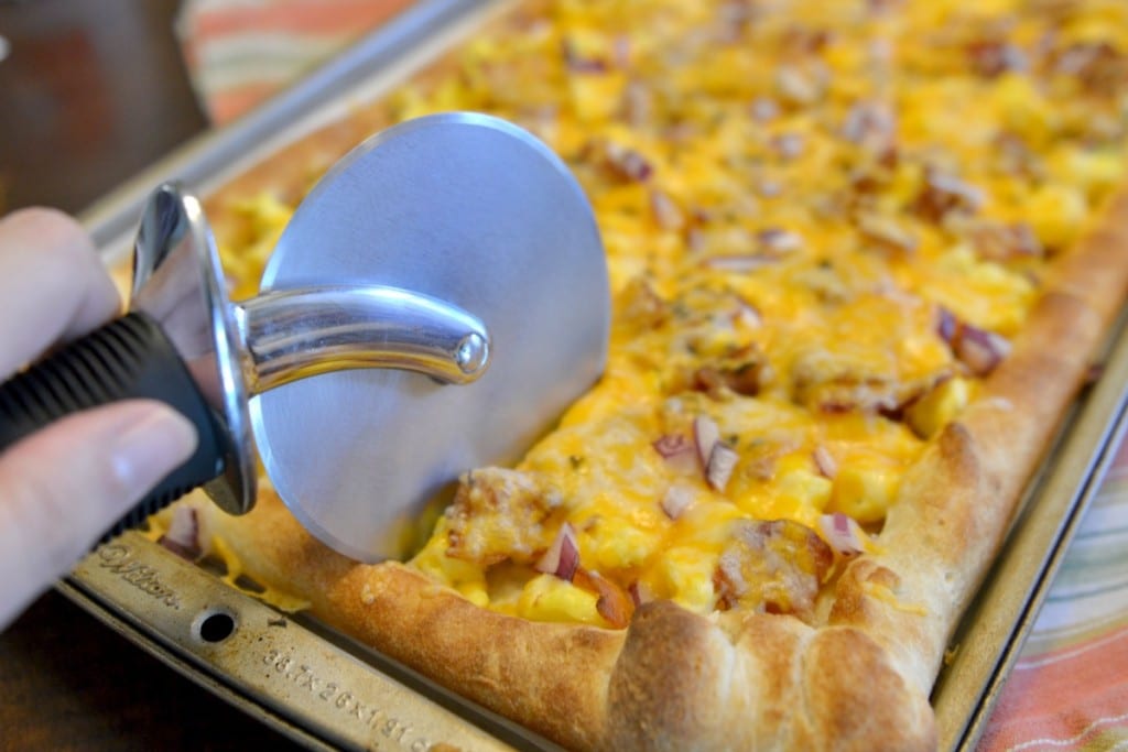 Cut breakfast pizza using a pizza cutter and serve. 