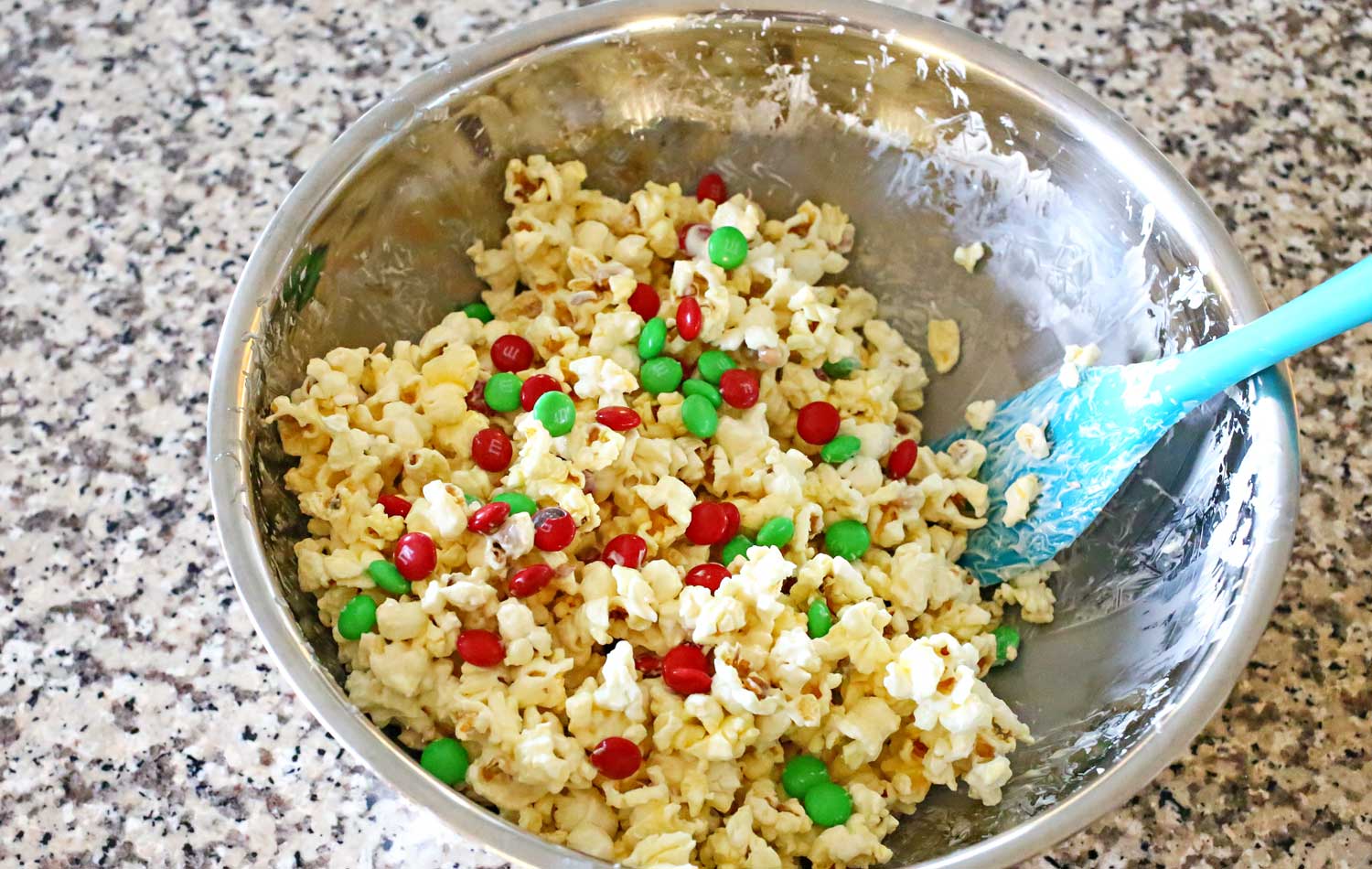 Add the popcorn to a bowl, stir in the white chocolate to coat and then add the red and green M&Ms. 