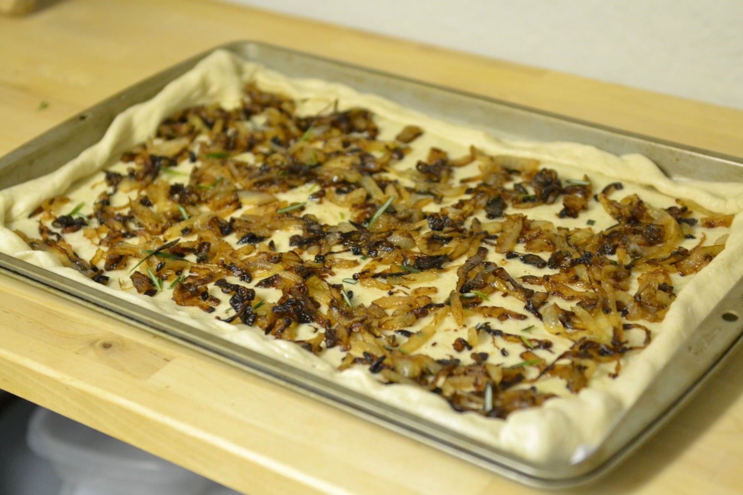 Spread caramelized onion over dough. Sprinkle with salt and fresh rosemary, then fold edges over top of onions.