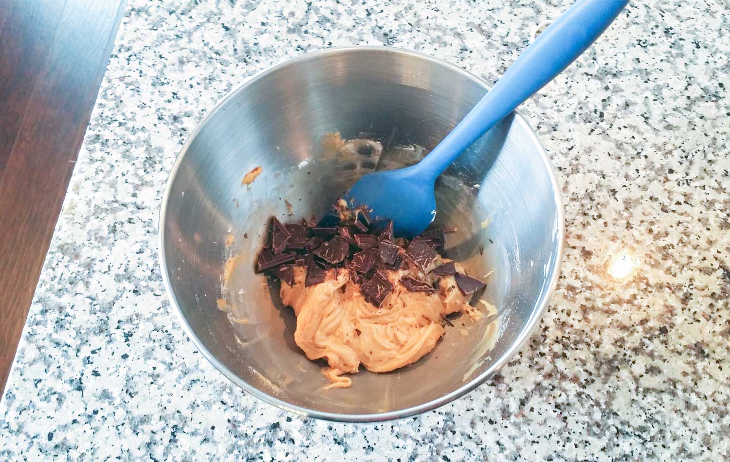 Add chopped pieces of chocolate to peanut butter mixture in bowl and stir with a spoon.