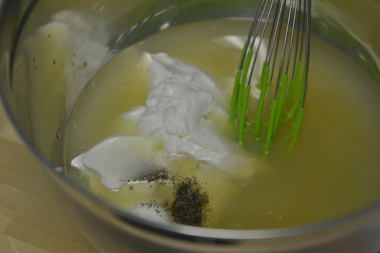 In large bowl, whisk together olive oil, white wine, chicken broth, sour cream, salt, and pepper.