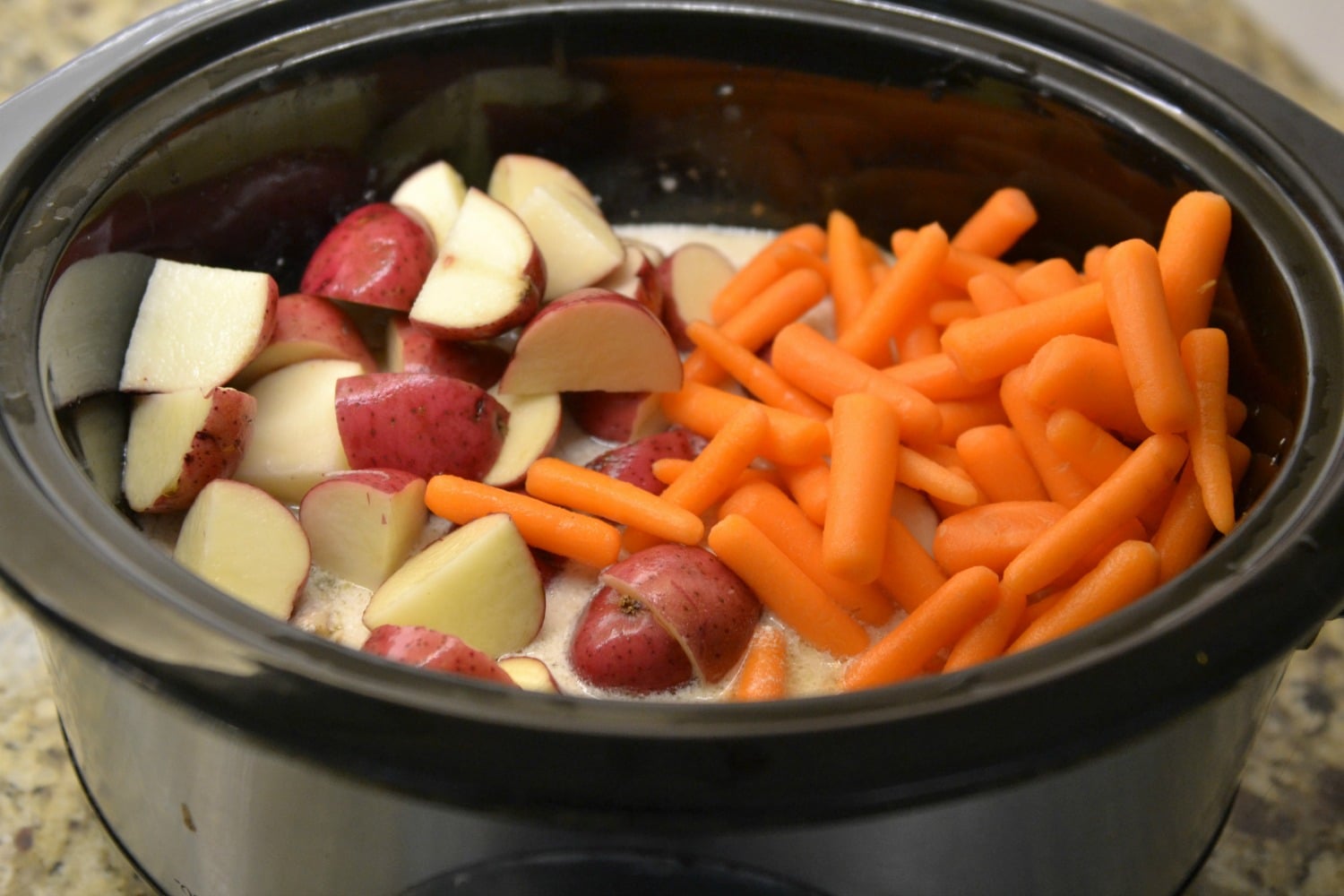 Add baby red potatoes and baby carrots to crockpot over chicken. 
