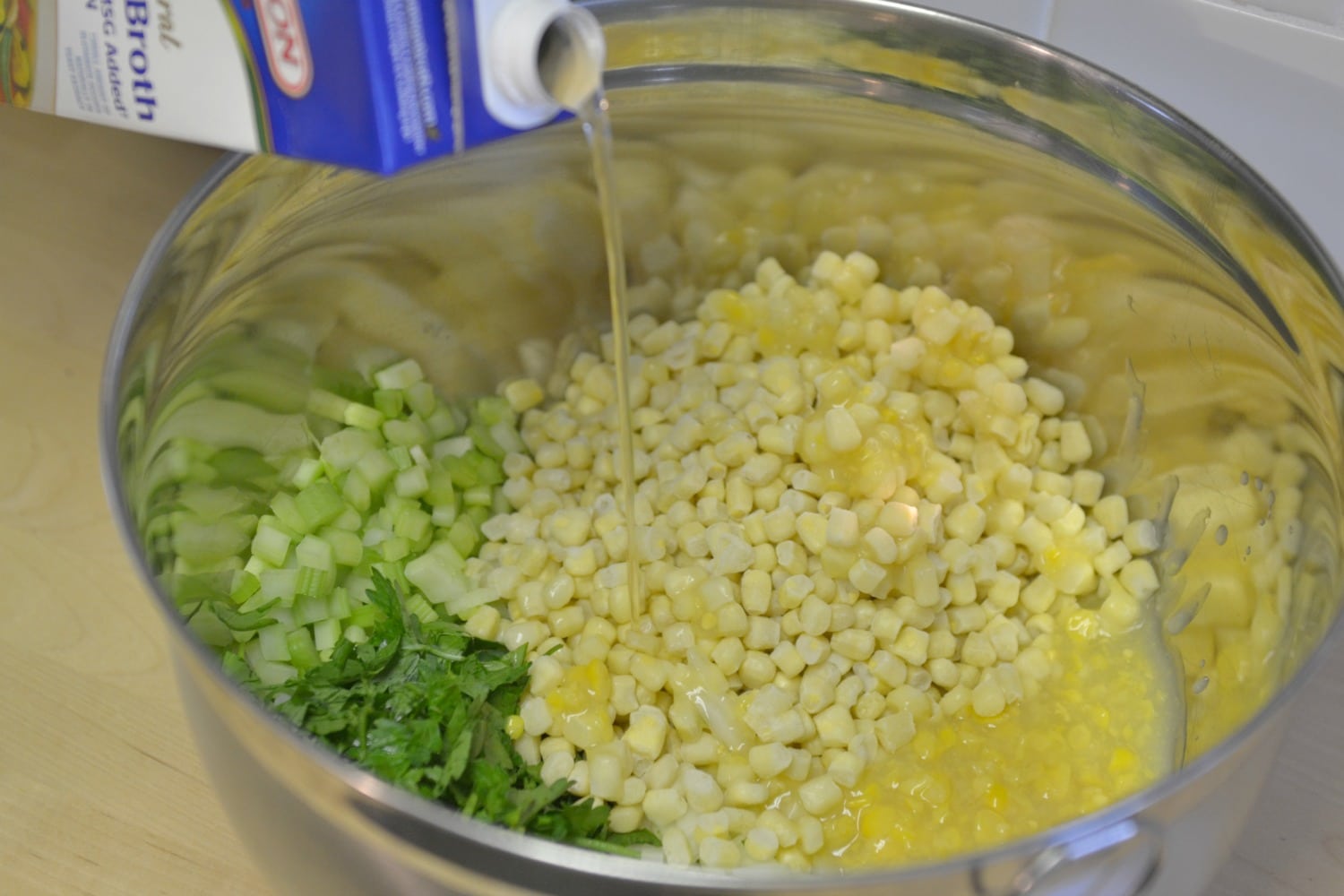 In large bowl, mix together onions, parsley, celery, creamed corn, frozen corn, and broth.