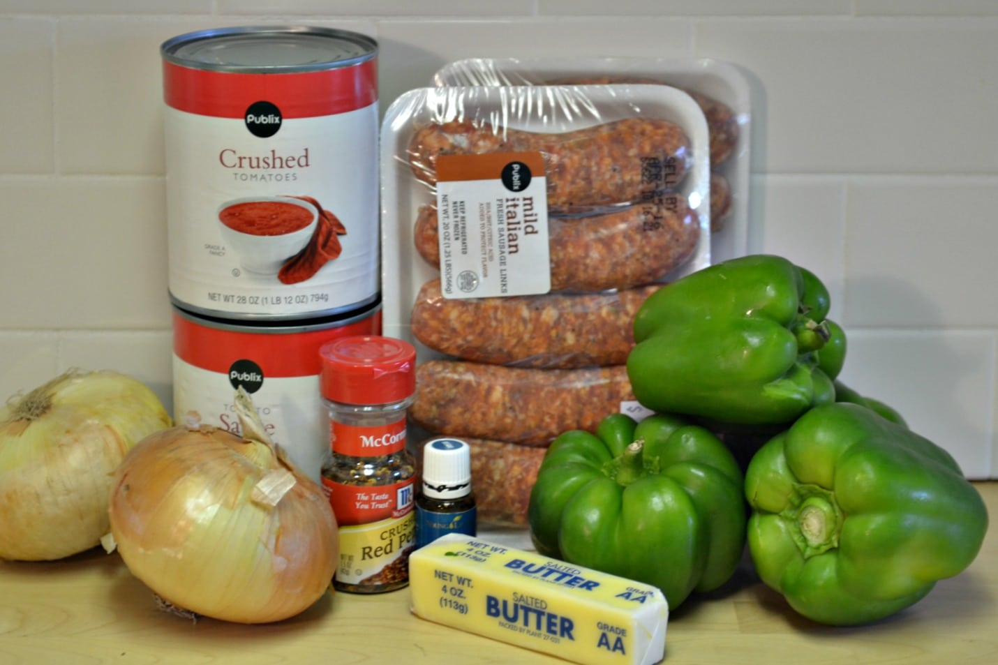 Gather the ingredients for these yummy slow cooker sausage and peppers: onion, tomatoes, spices, butter, peppers and of course, sausage. 