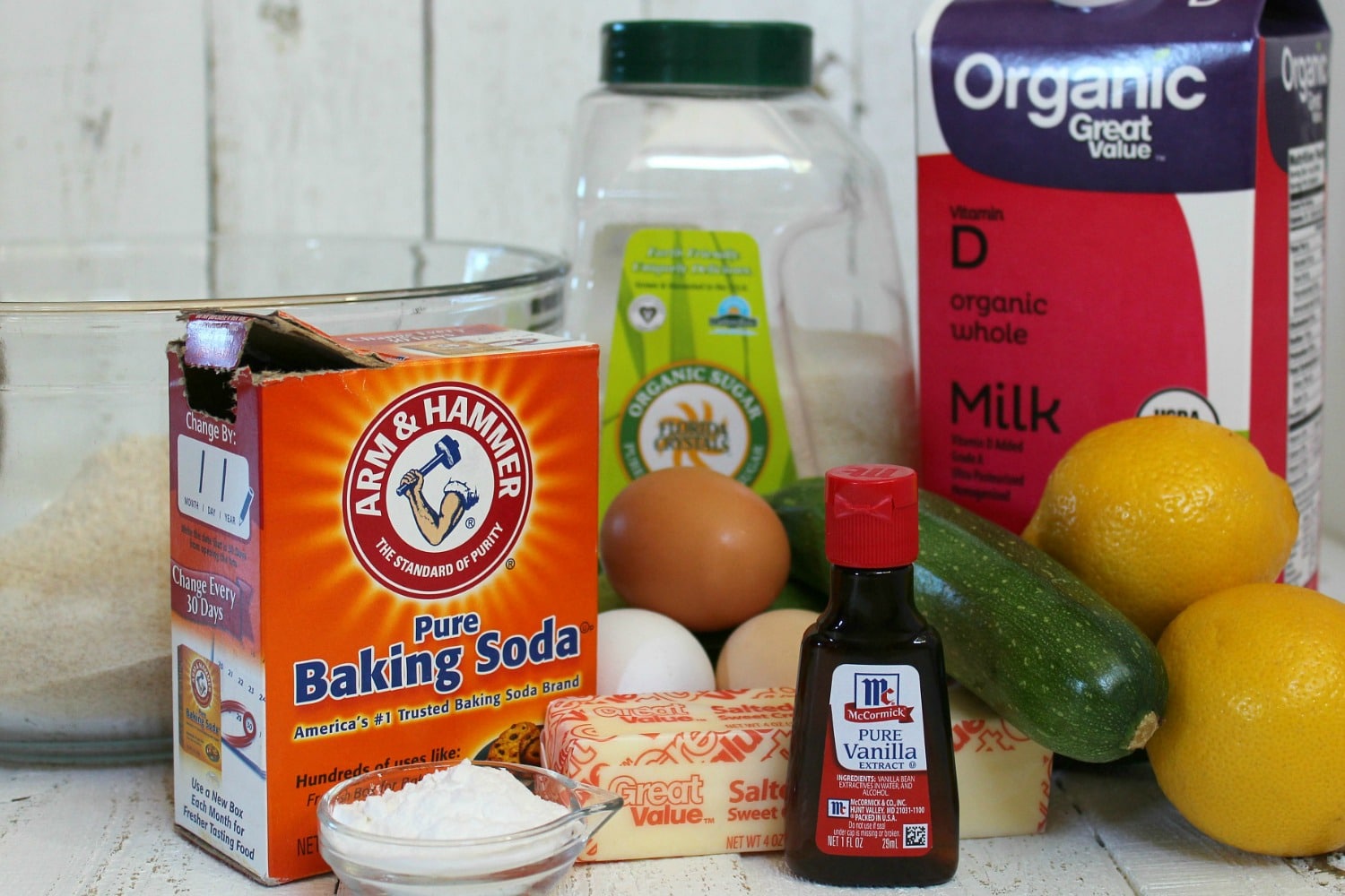 Assemble your ingredients for the lemon zucchini pancakes: flour, sugar, baking powder, baking soda, eggs, butter, milk, lemon juice, lemons, vanilla extract and zucchini. 