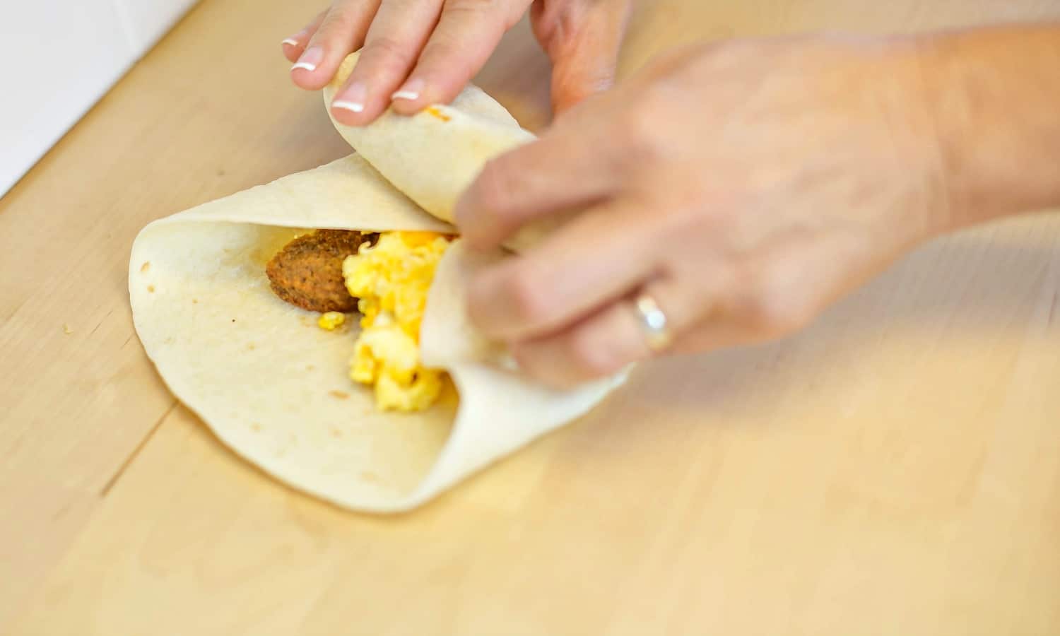 Add eggs and sausage, plus any other ingredients, into the tortilla and roll into a burrito