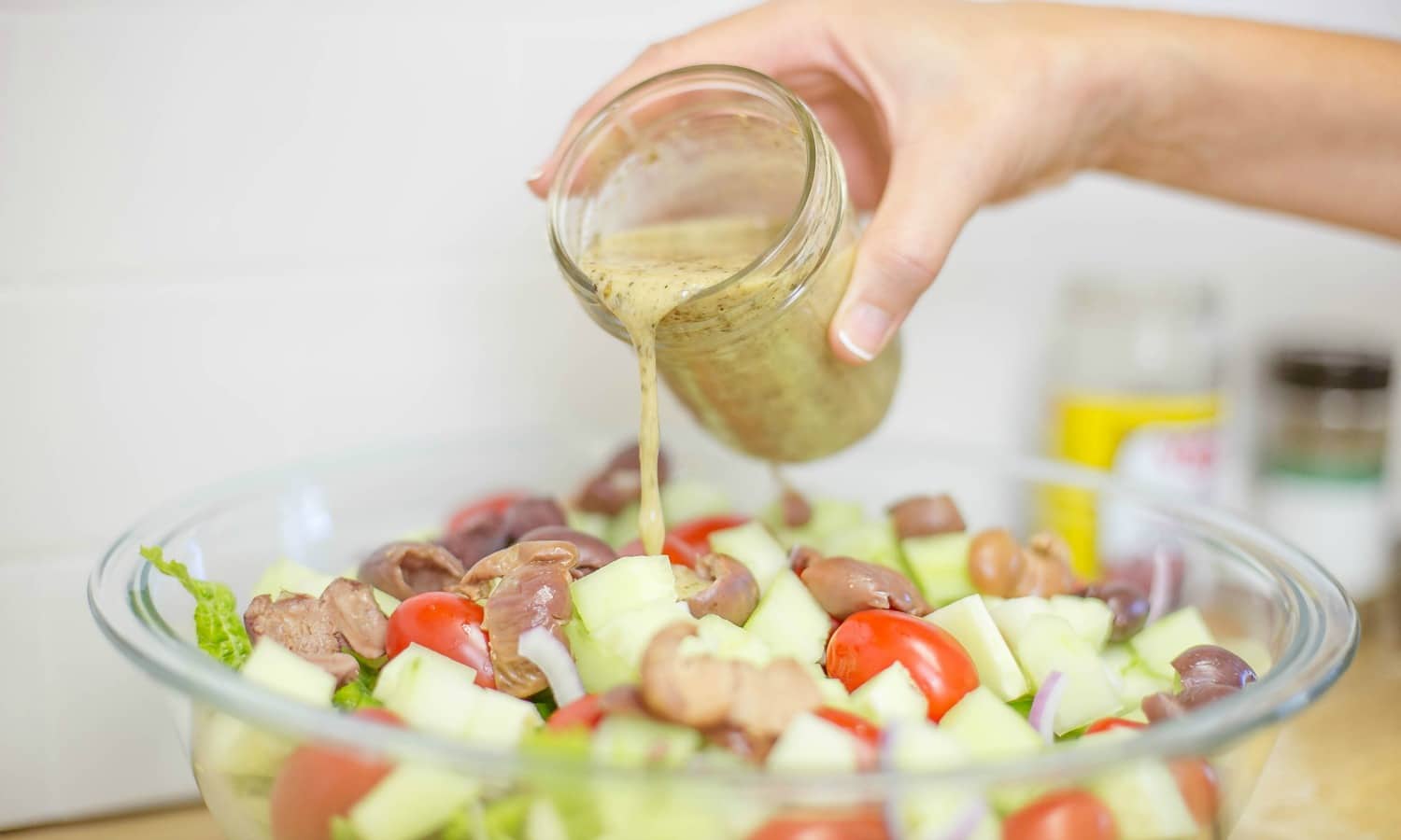 n large bowl; combine lettuce, peppers, tomatoes, olives, red onion, and cucumber . Mix dressing again and toss with salad.