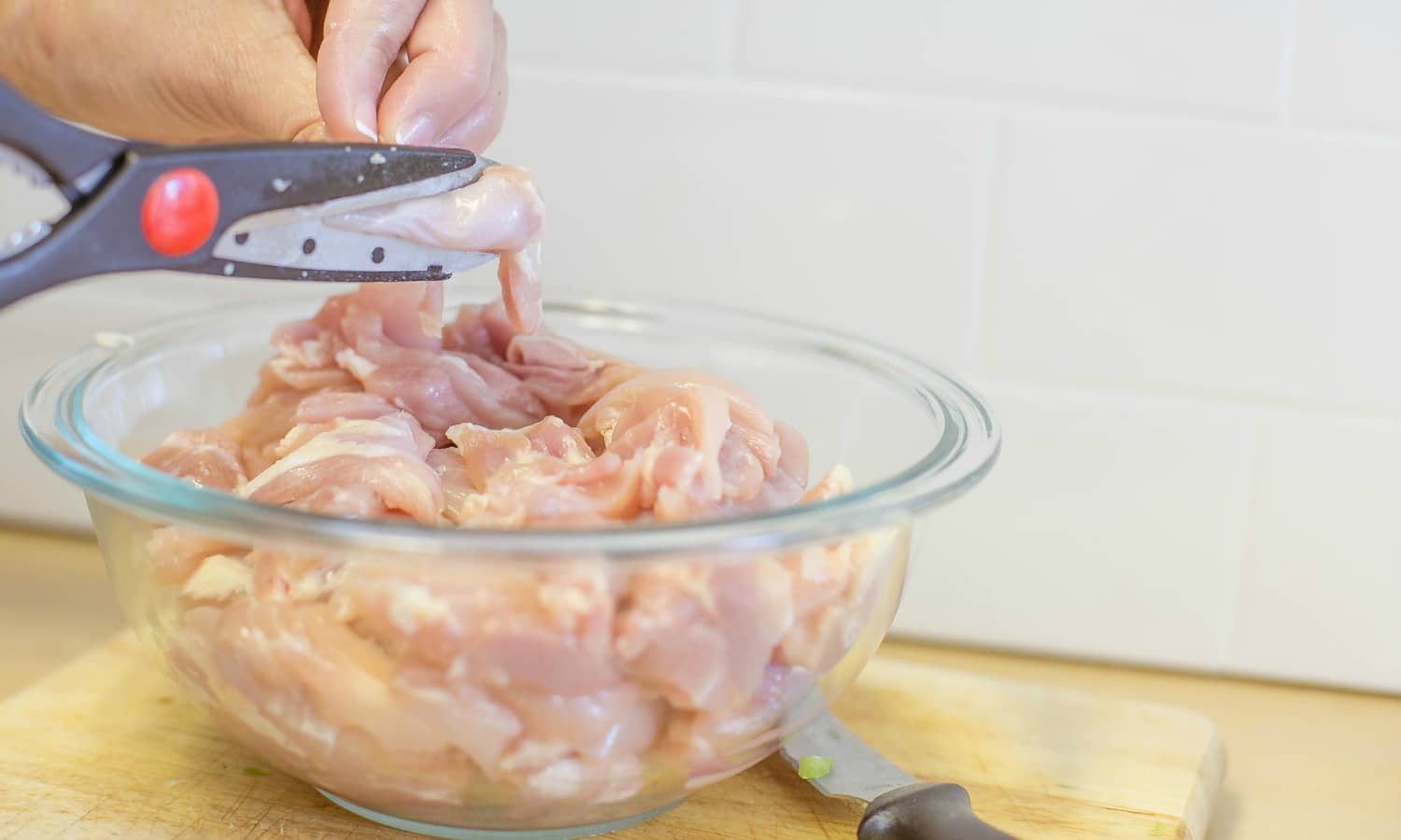 Use kitchen shears to cut the raw chicken into small, diced chunks. 