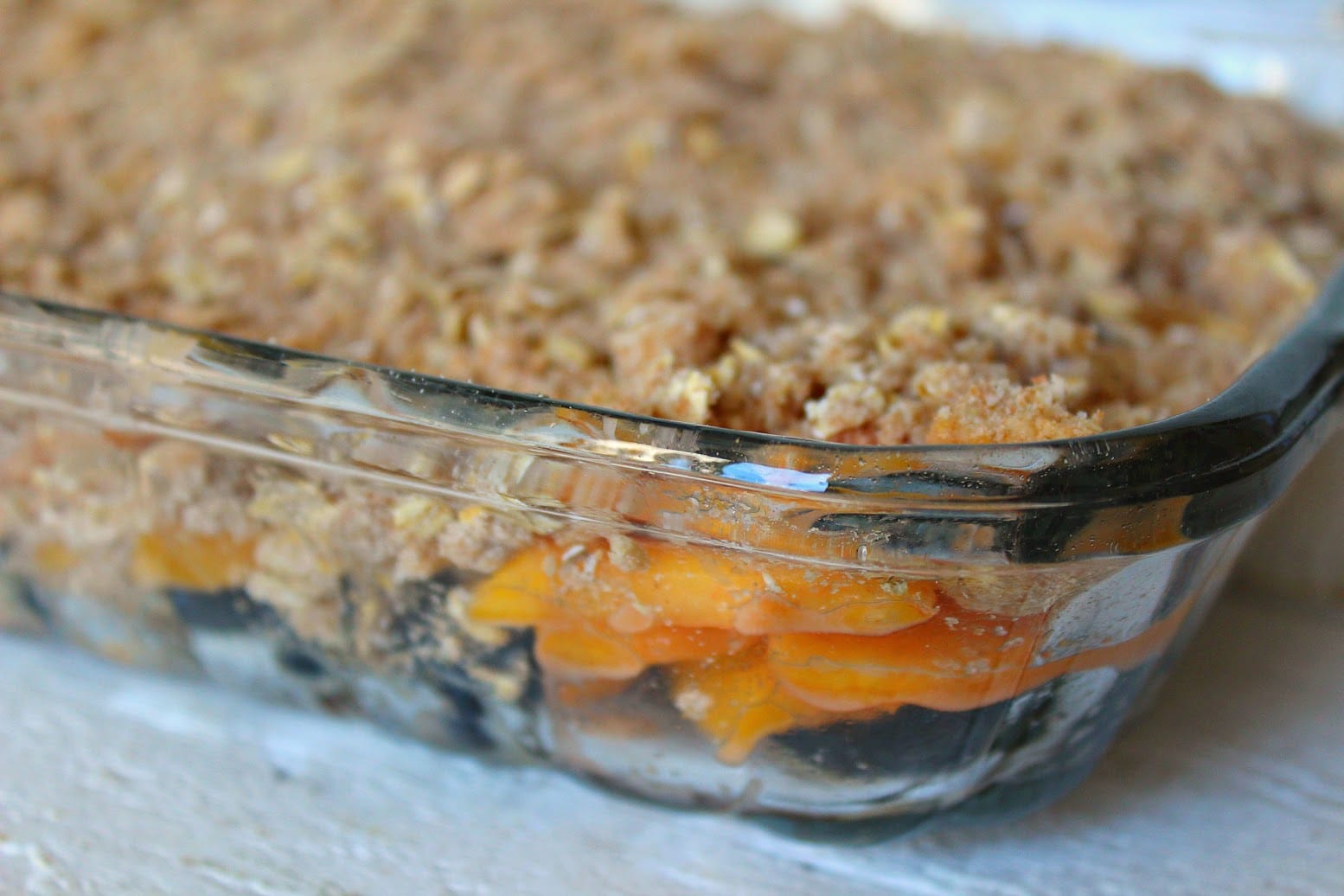 Pour the peaches and blueberries into a shallow glass baking dish and cover with the crumble topping. 