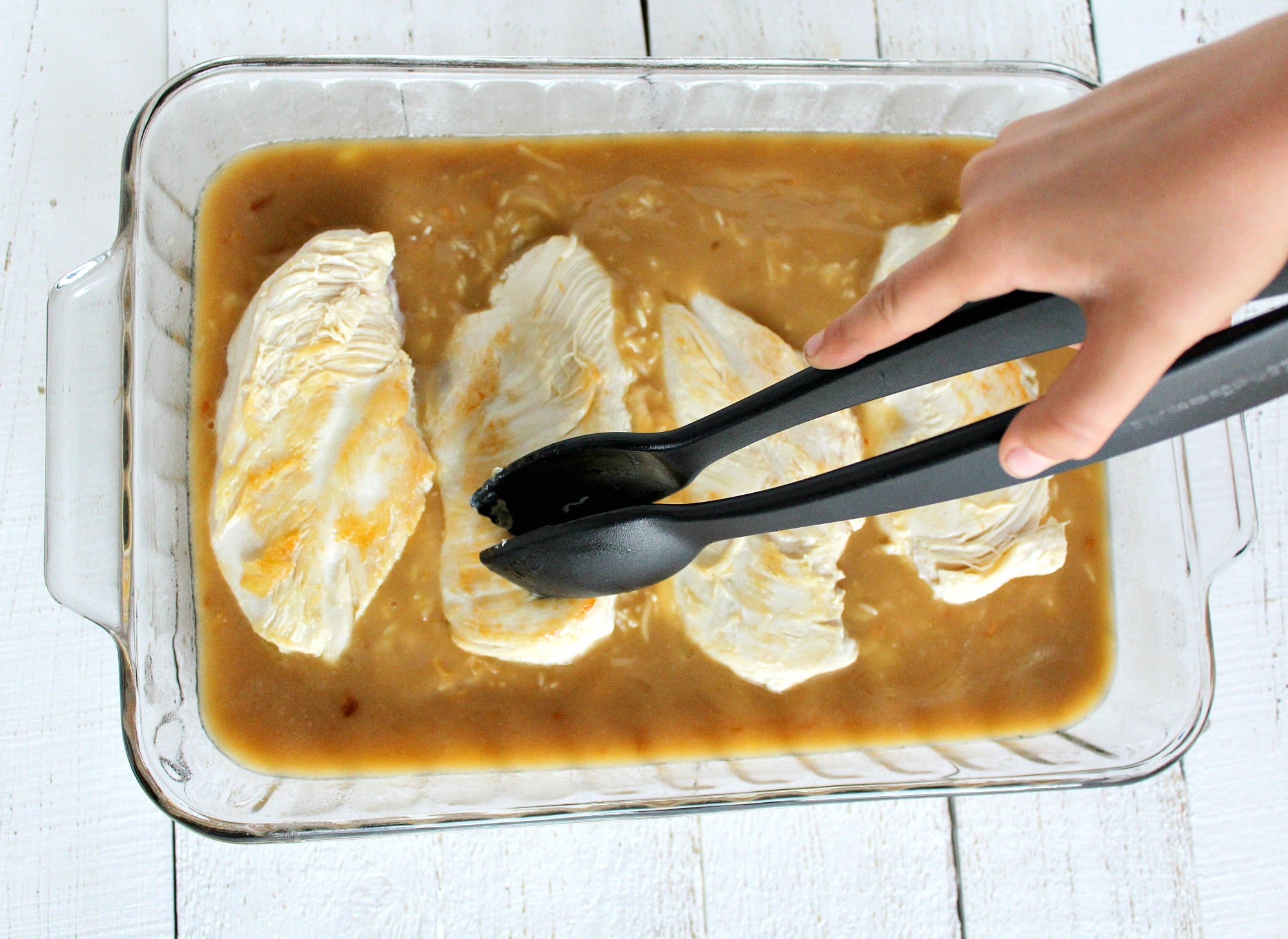 Transfer the browned chicken breasts into the casserole dish using tongs. 