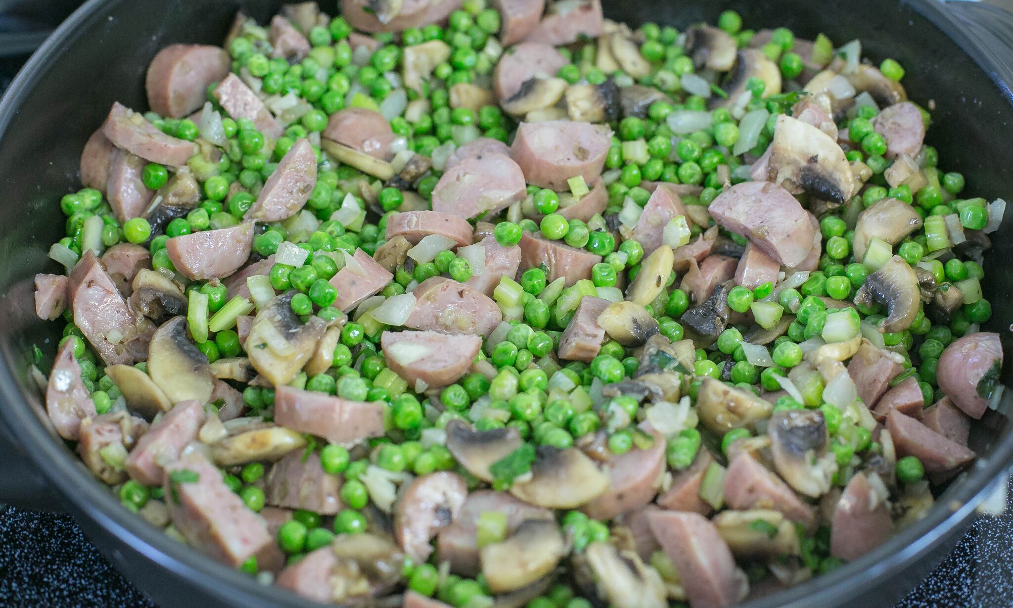 Add sausage and frozen peas to pan and mix well. 