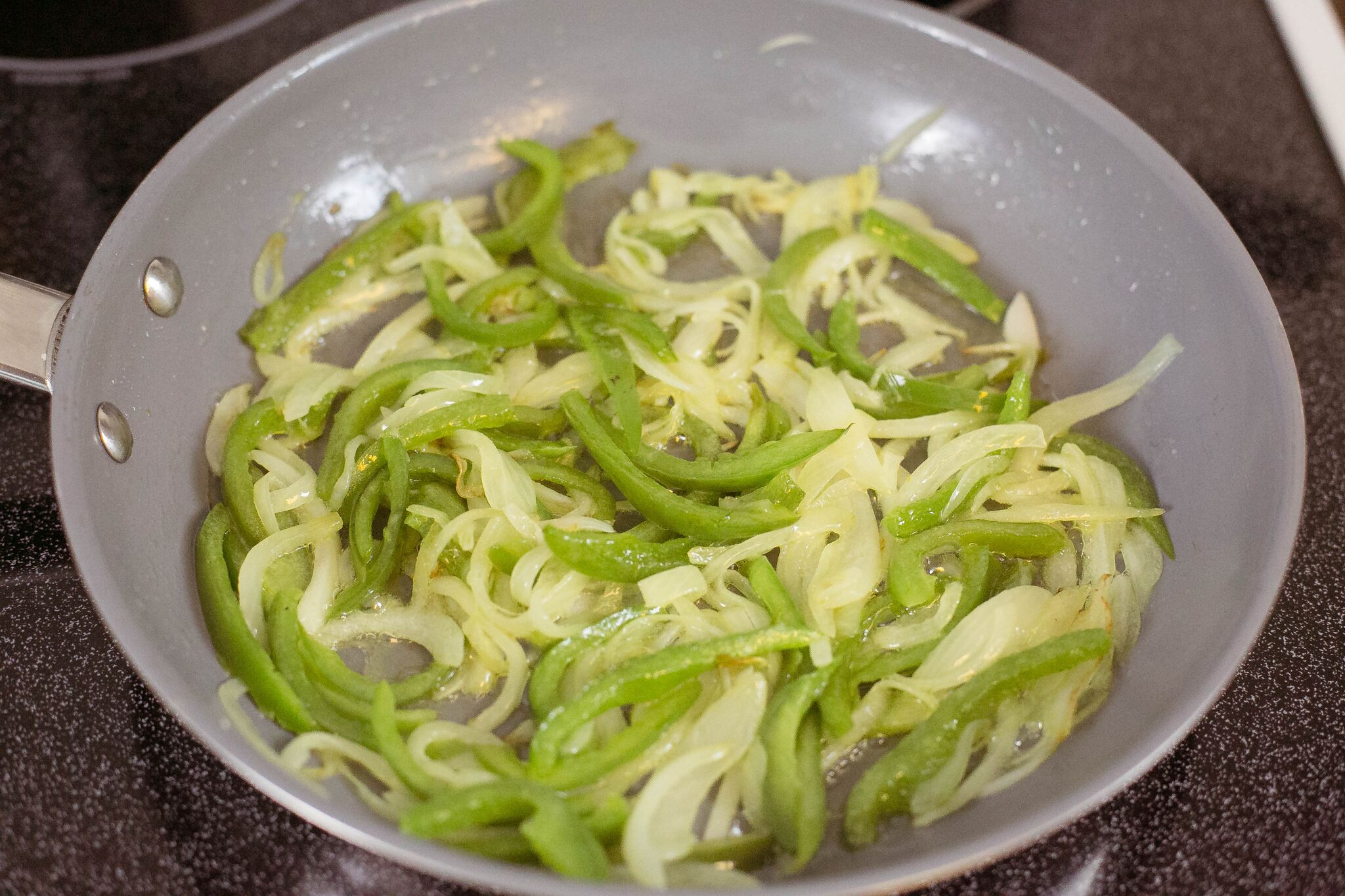 Melt butter in a large pan and saute peppers and onions until soft. 