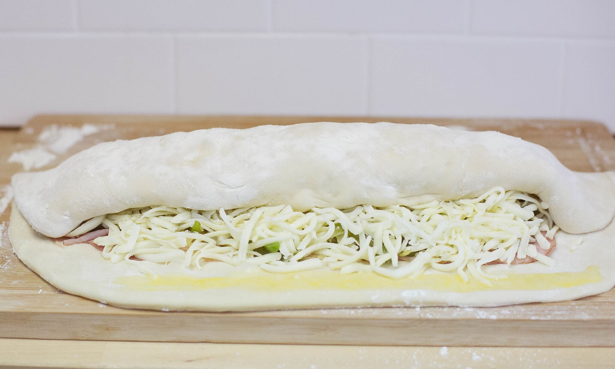 Coat the boarder of the dough with egg wash then begin rolling it up. 