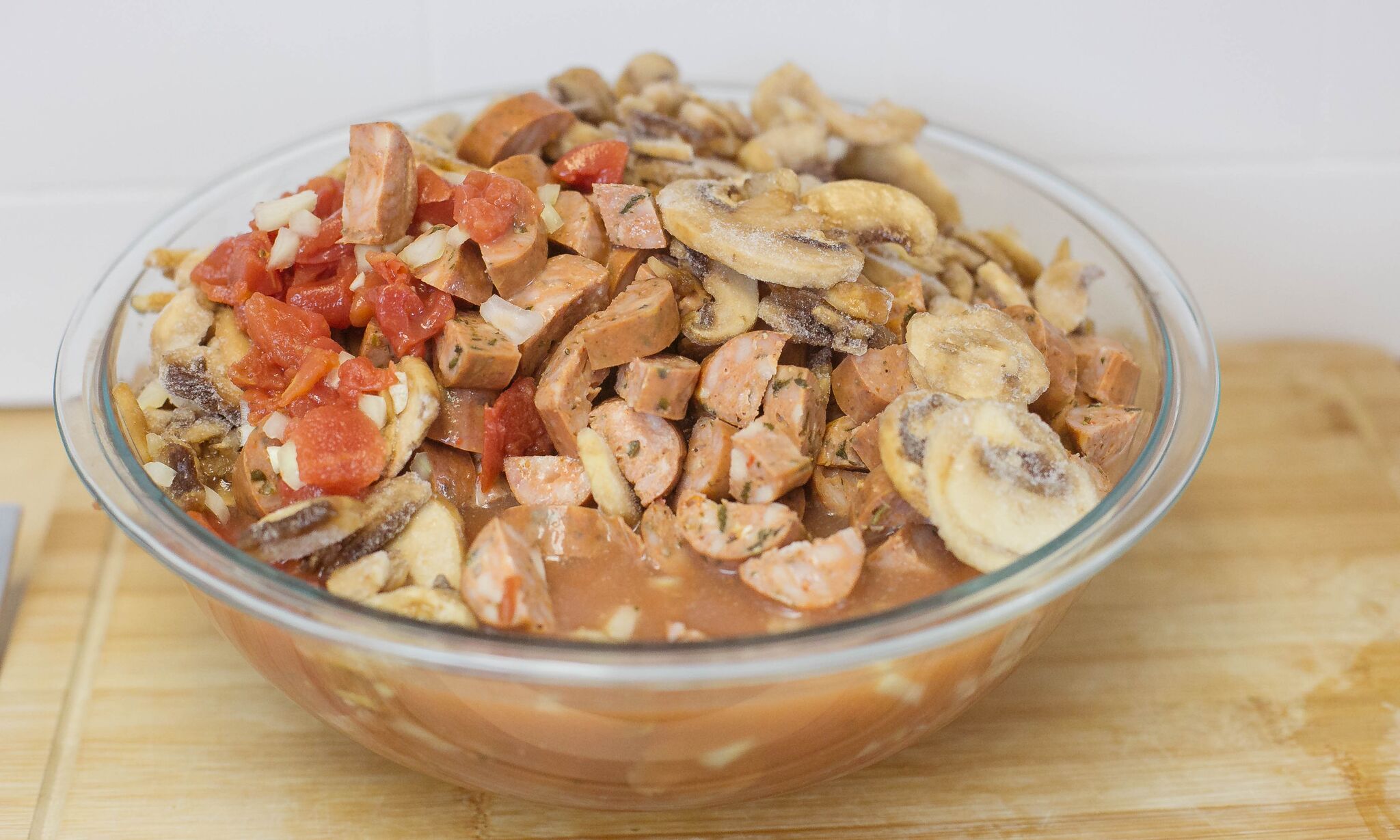 In large bowl, mix together diced tomatoes, sliced mushrooms, onion, garlic, sausage and chicken stock.