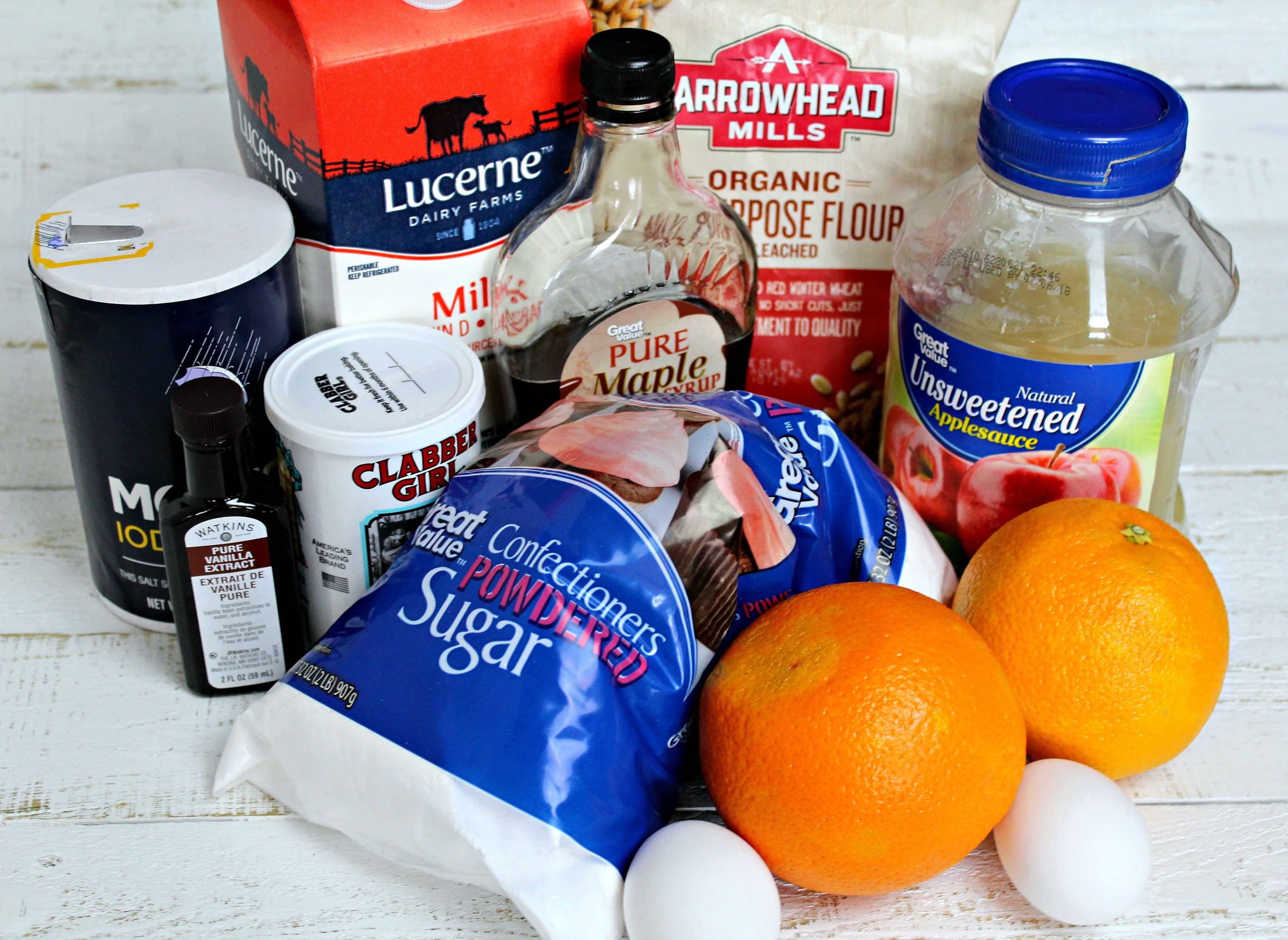 Assemble your ingredients for the pancake bites: flour, baking powder, salt, milk, maple syrup, eggs, applesauce, vanilla extract, orange zest, powdered sugar, vanilla extract and fresh orange juice. 