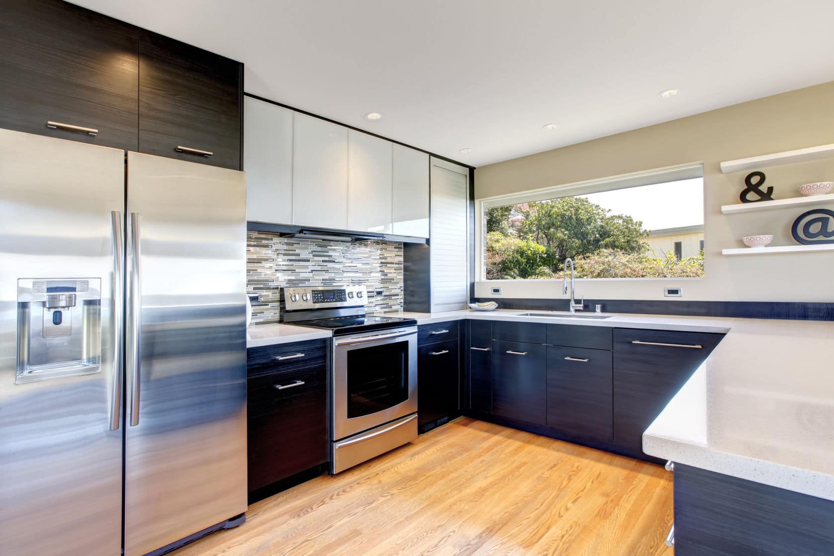 A clean kitchen with shiny counter tops and a wood floor. 