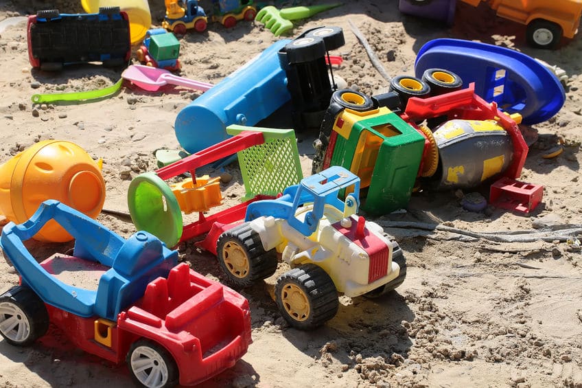 A pile of beach toys in the sand. 