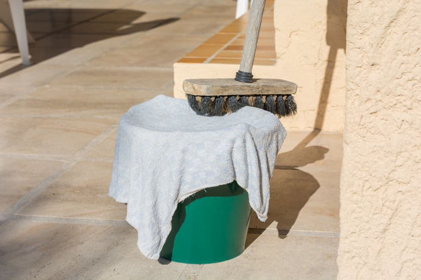 A bucket, towel and outside cleaning brush are stacked together. 