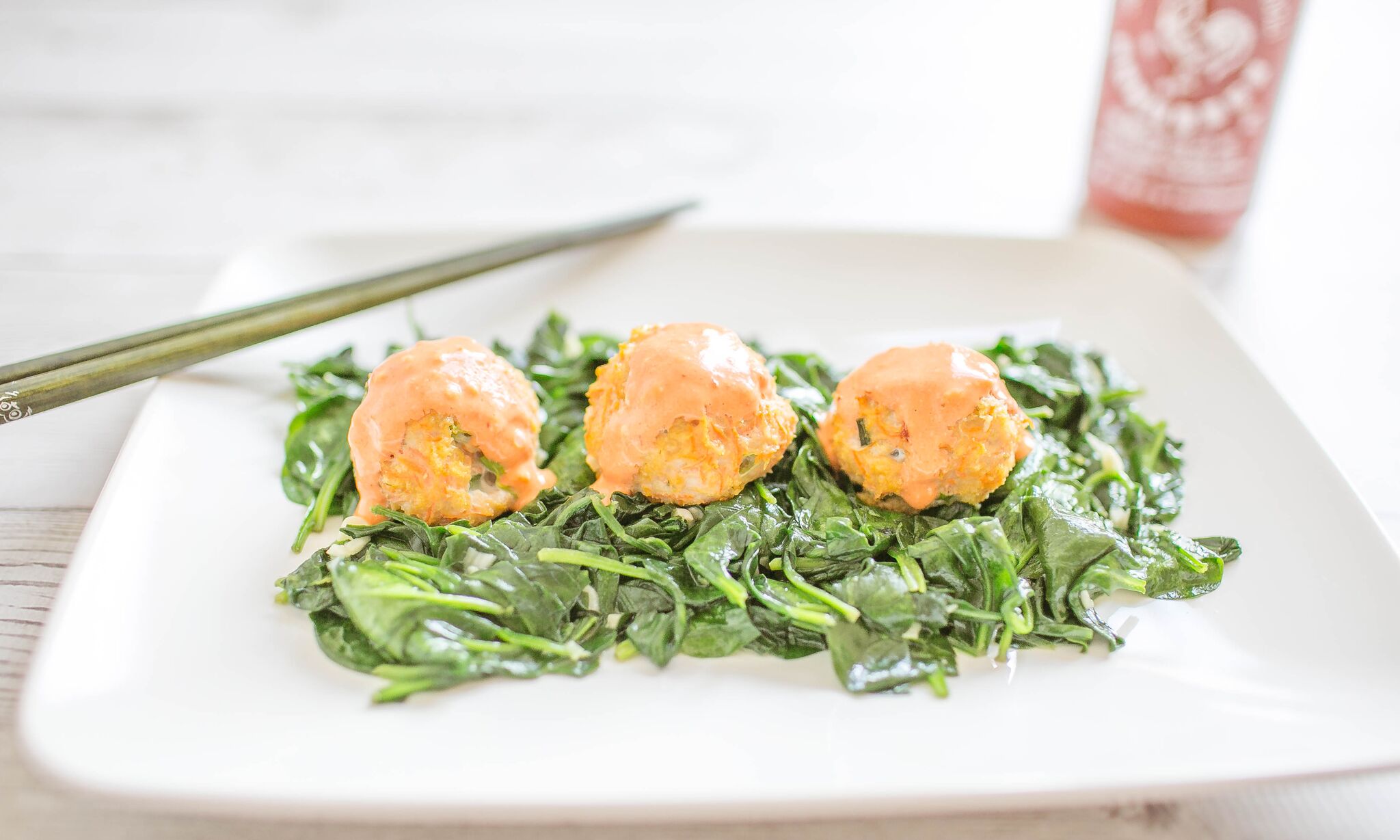 Serve chicken meatballs with sriracha sauce over a fresh greens. 