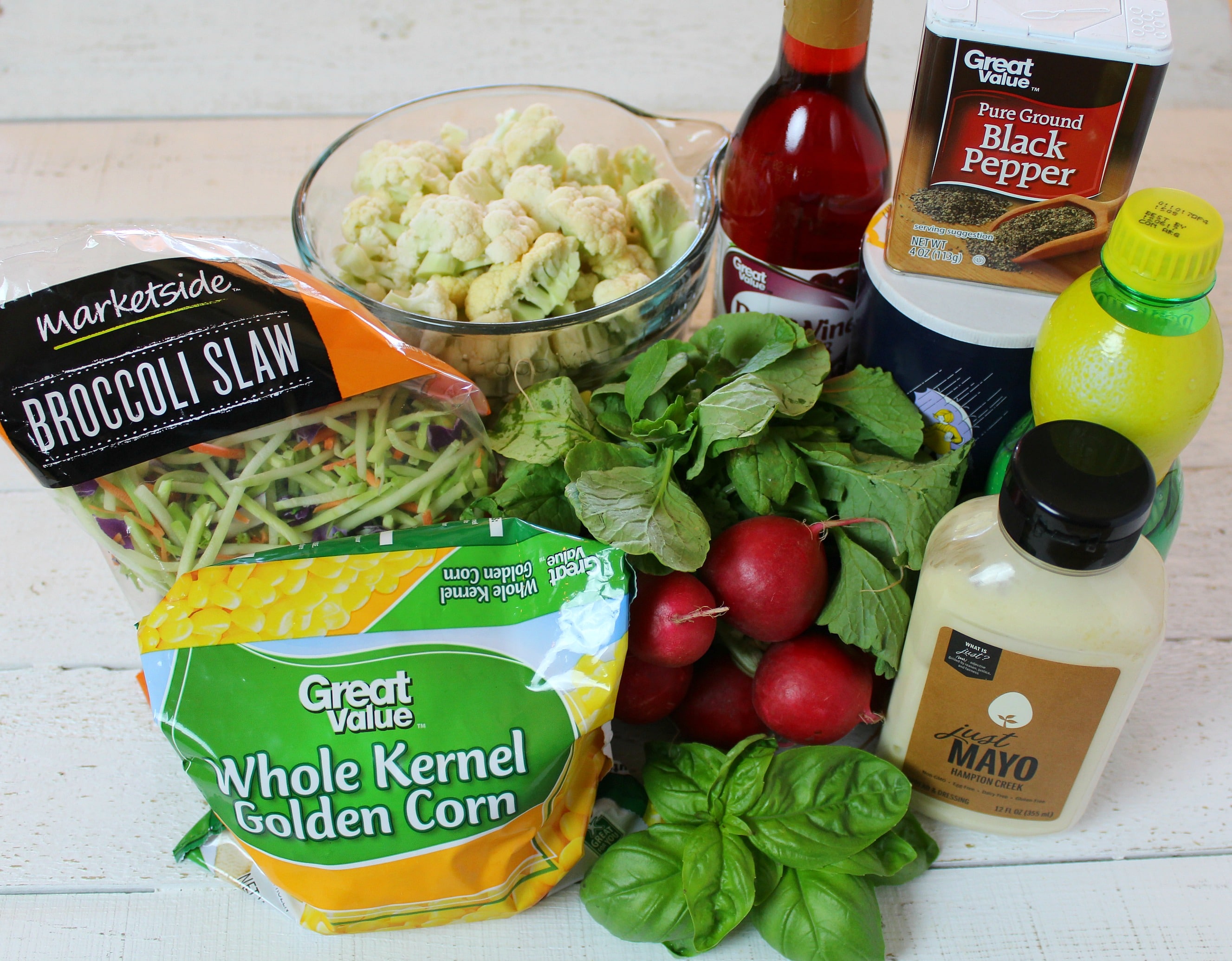 Assemble your ingredients: broccoli slaw, frozen corn, radishes, cauliflower, fresh basil, lemon juice, red wine vinegar, mayo, sea salt, black pepper