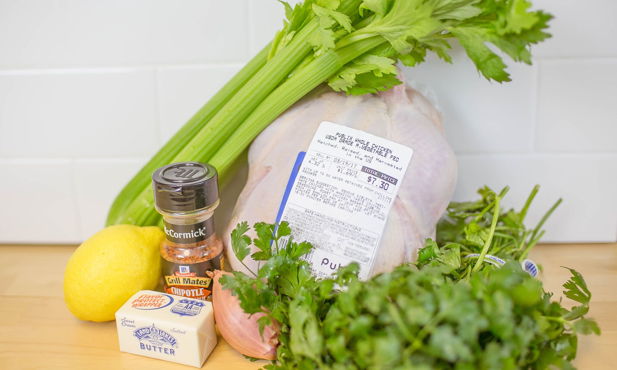 Gather your ingredients: Parsley, shallot, lemon, butter, whole chicken, Grill Mates Chipotle & Roasted Garlic seasoning, and celery. 